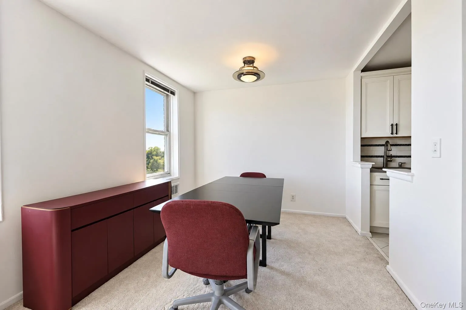 Bright interior with neutral carpeting, recessed lighting, and a built-in wet bar featuring white cabinetry, a black faucet, and a tile backsplash Bright interior with neutral carpeting, recessed lighting, and a built-in wet bar featuring white cabinetry, a black faucet, and a tile backsplash