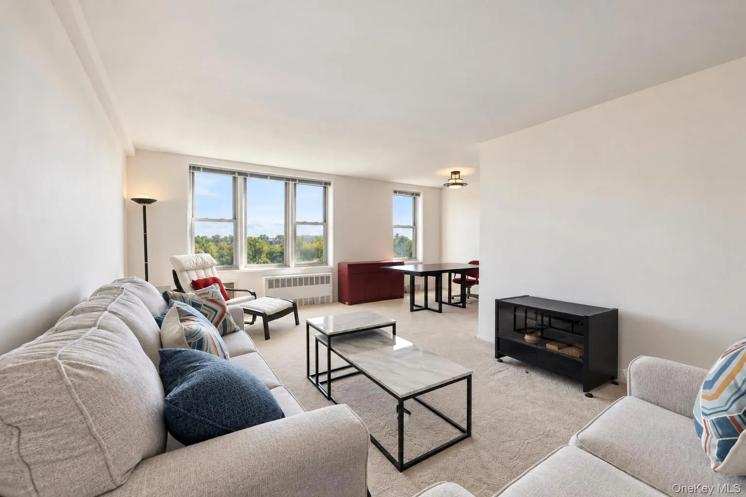 Expansive living area featuring light-colored carpeting and bright white walls Expansive living area featuring light-colored carpeting and bright white walls