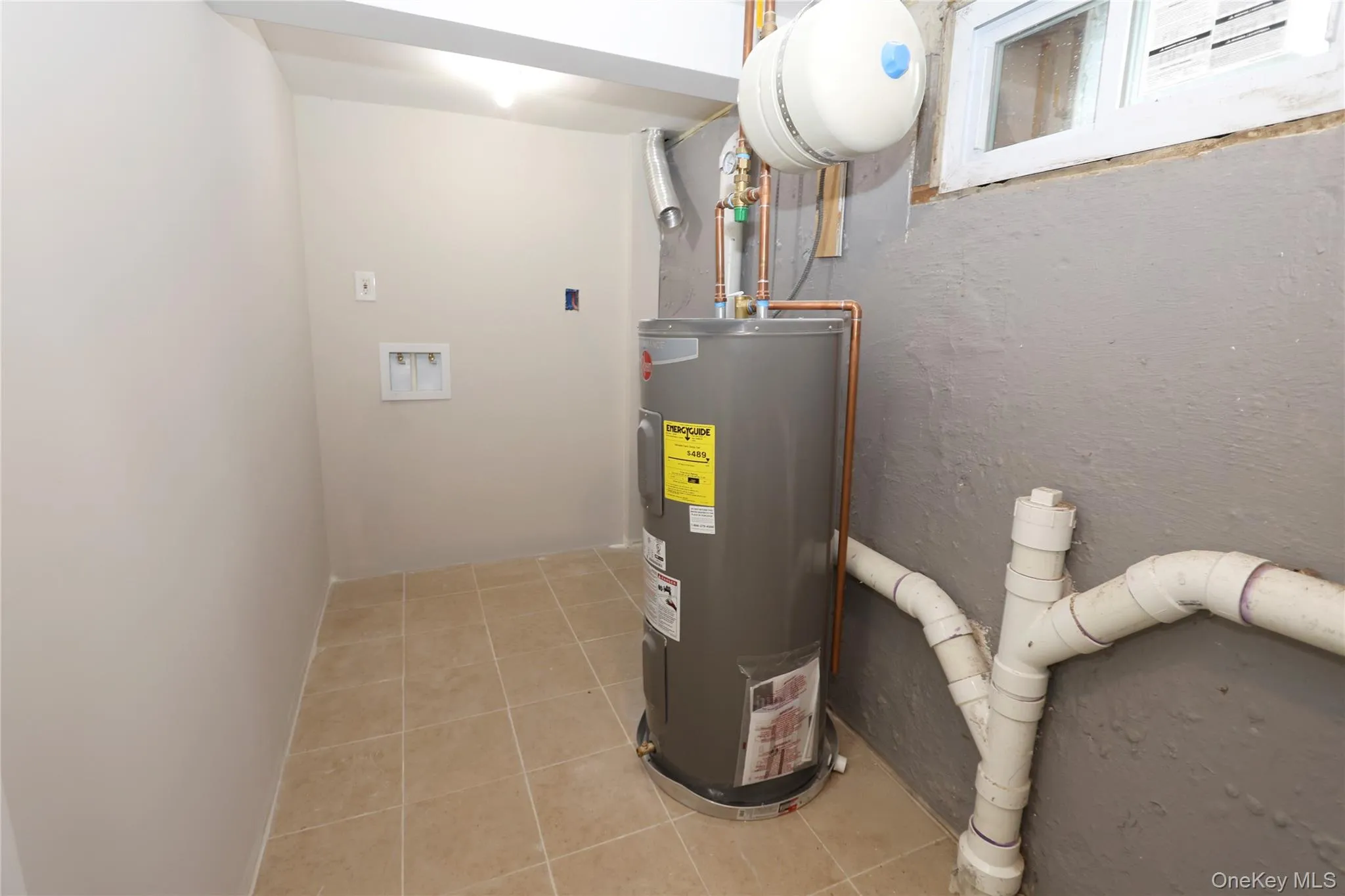 Tiled flooring, water heater, and visible plumbing Tiled flooring, water heater, and visible plumbing