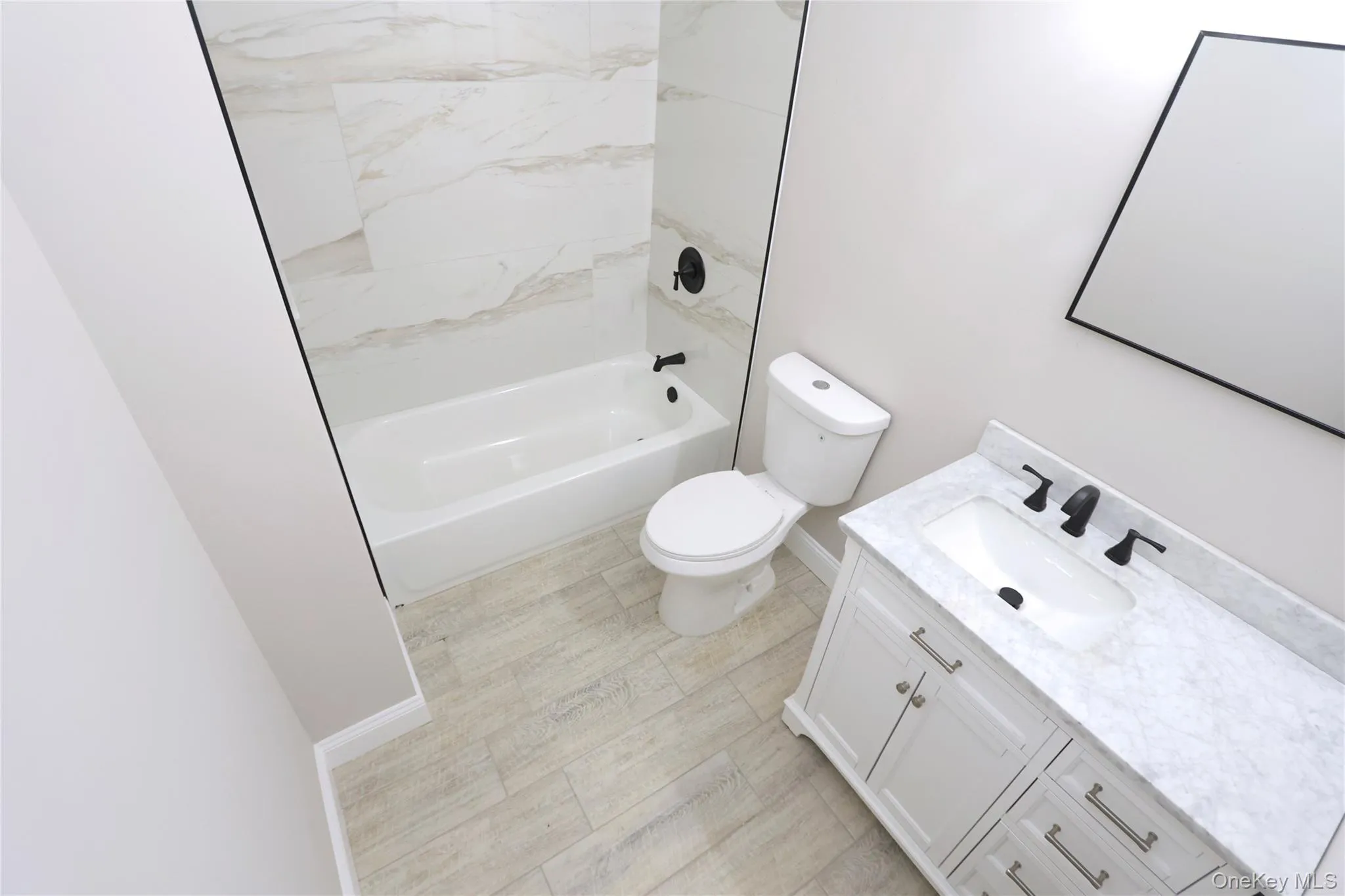 White vanity with a stone countertop, undermount sink, and matte black fixtures White vanity with a stone countertop, undermount sink, and matte black fixtures