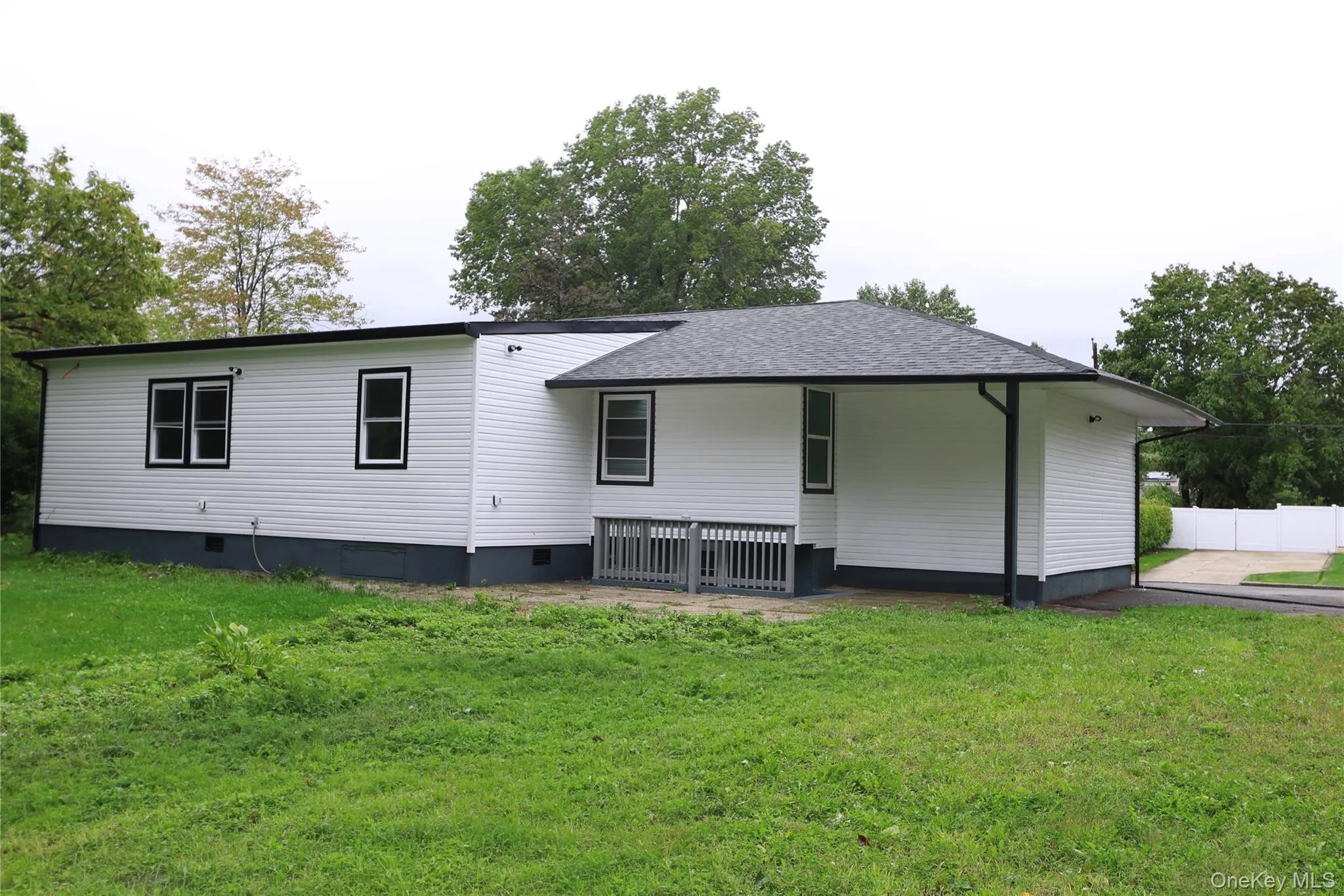 White vinyl siding exterior with black trim windows, a gray shingle roof, and a covered patio area White vinyl siding exterior with black trim windows, a gray shingle roof, and a covered patio area