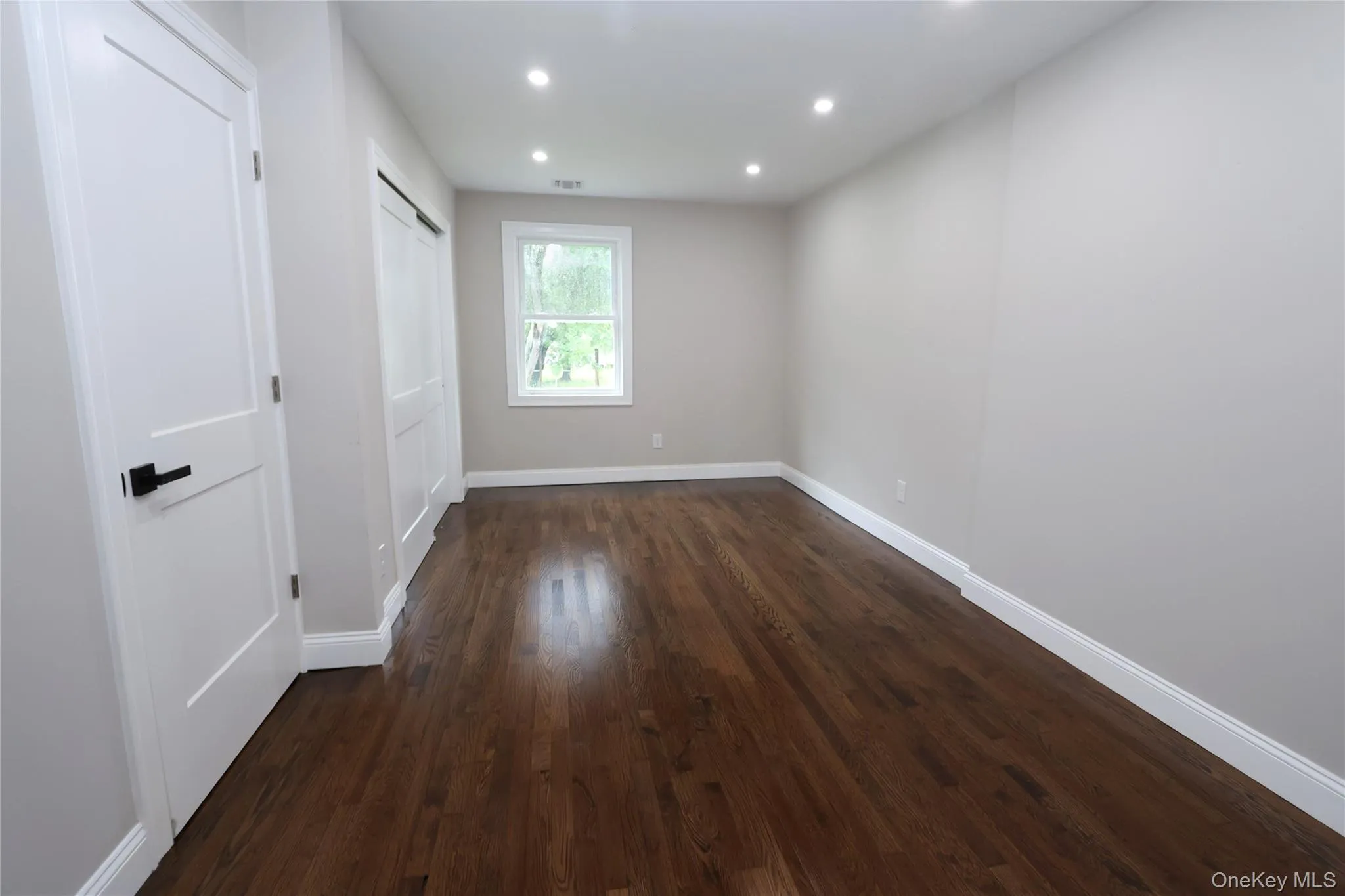 Recessed lighting, wood-finish flooring, white trim, flat-panel interior doors with matte black hardware, and a single window Recessed lighting, wood-finish flooring, white trim, flat-panel interior doors with matte black hardware, and a single window