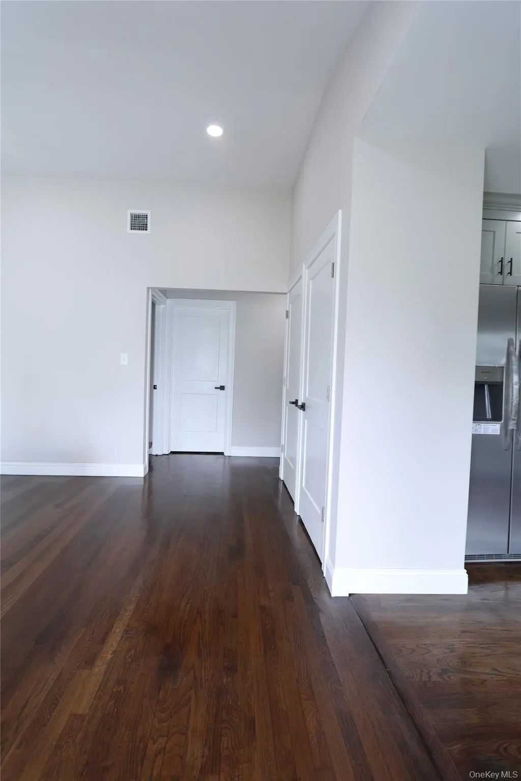 Dark wood-finish flooring, recessed ceiling lighting, white walls, and white panel doors Dark wood-finish flooring, recessed ceiling lighting, white walls, and white panel doors