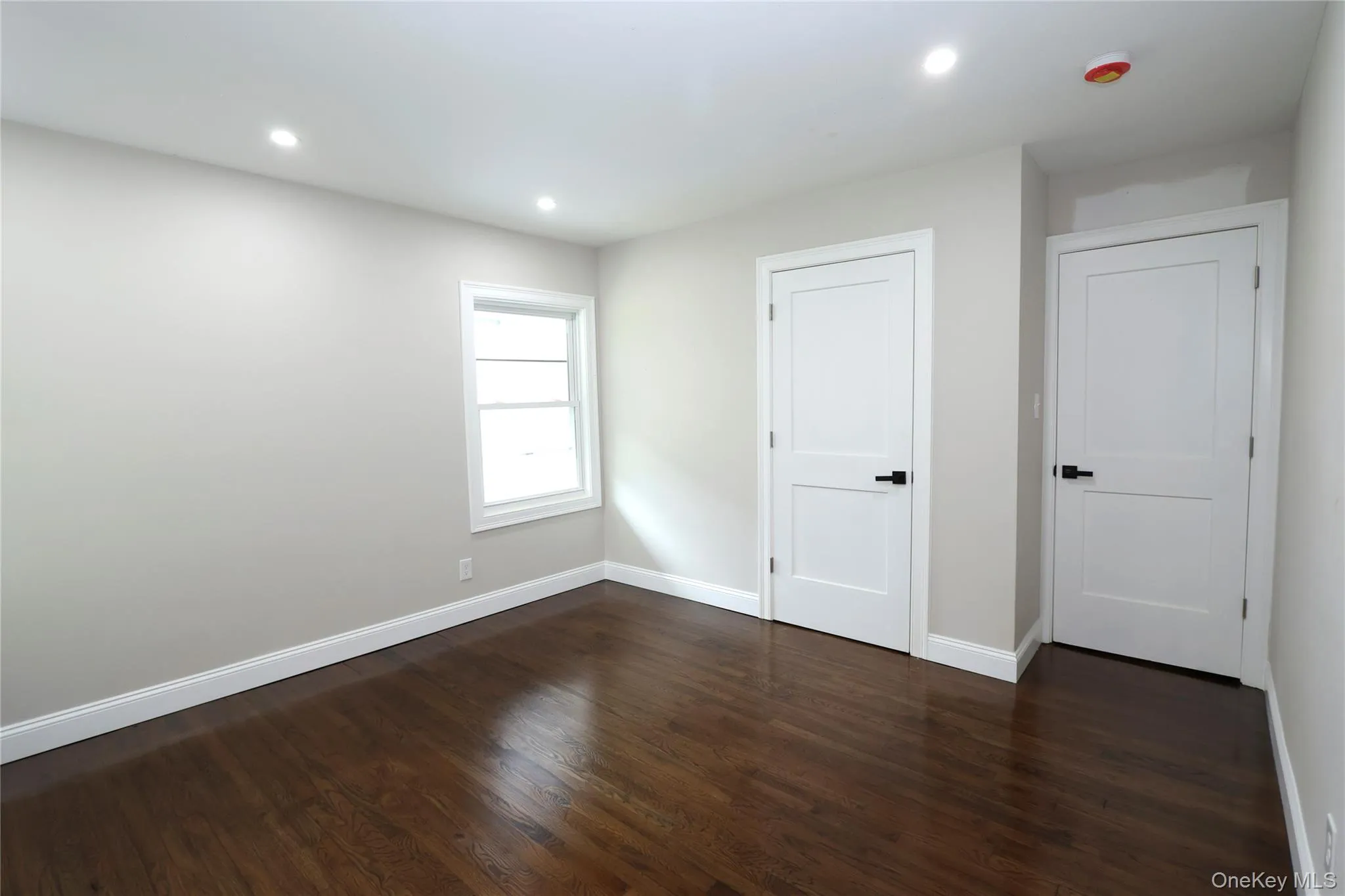 Rich wood-finish flooring, recessed ceiling lighting, crisp white trim, two panel doors with matte black hardware, and a casement window Rich wood-finish flooring, recessed ceiling lighting, crisp white trim, two panel doors with matte black hardware, and a casement window