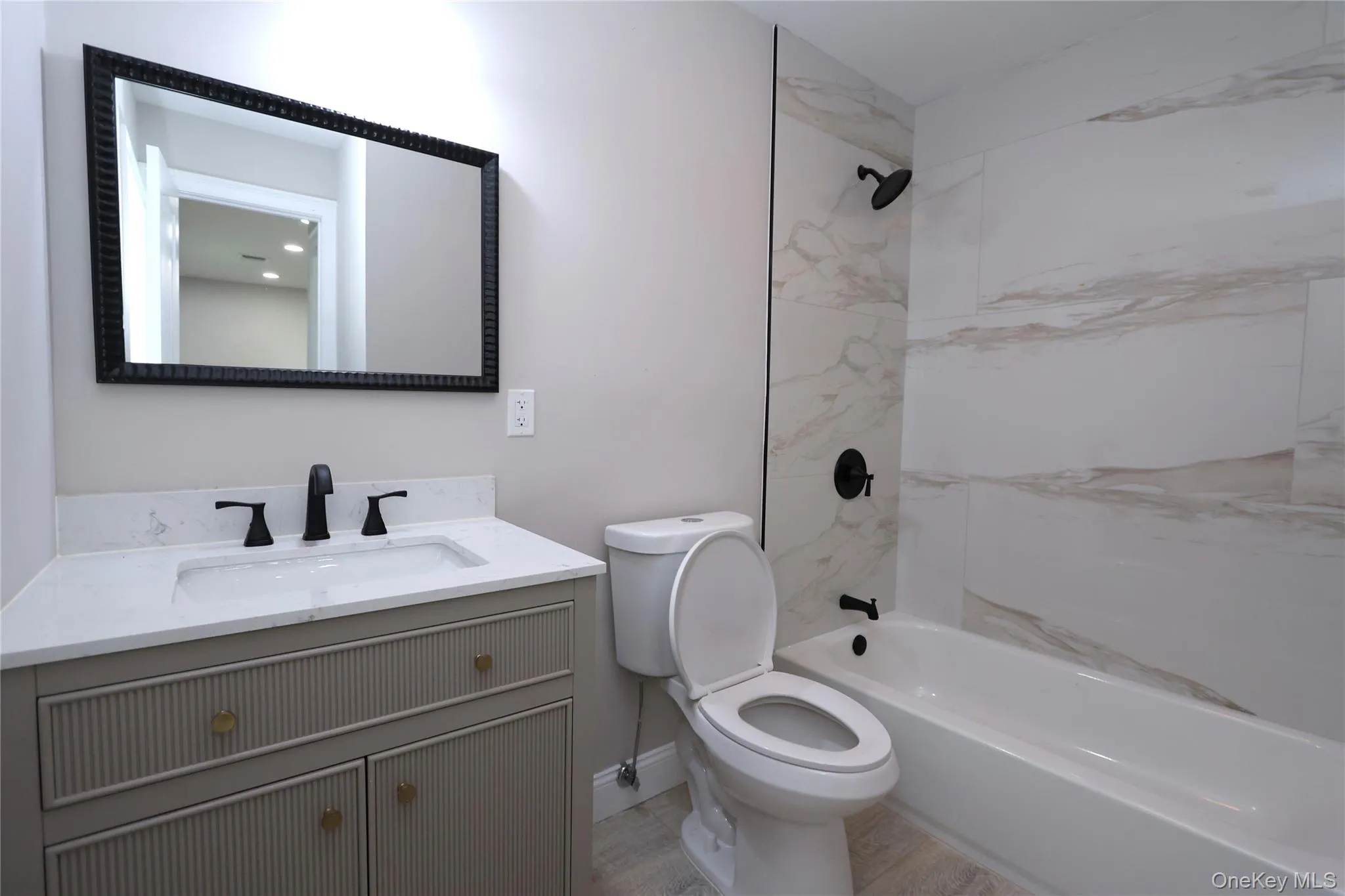 Vanity with a white countertop and integrated sink, matte black faucet, and a black framed mirror Vanity with a white countertop and integrated sink, matte black faucet, and a black framed mirror