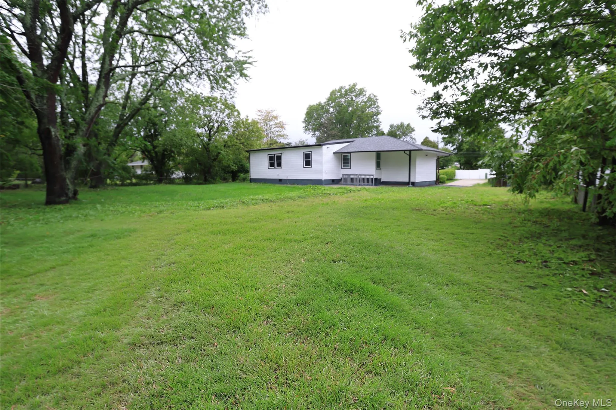 Expansive green lawn with mature trees and a single-story residence Expansive green lawn with mature trees and a single-story residence