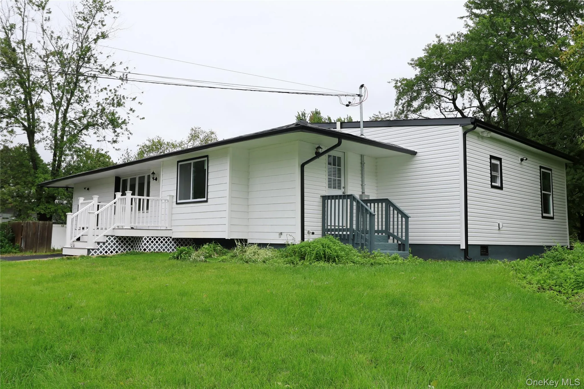 White exterior siding with dark trim accents and an expansive front lawn White exterior siding with dark trim accents and an expansive front lawn