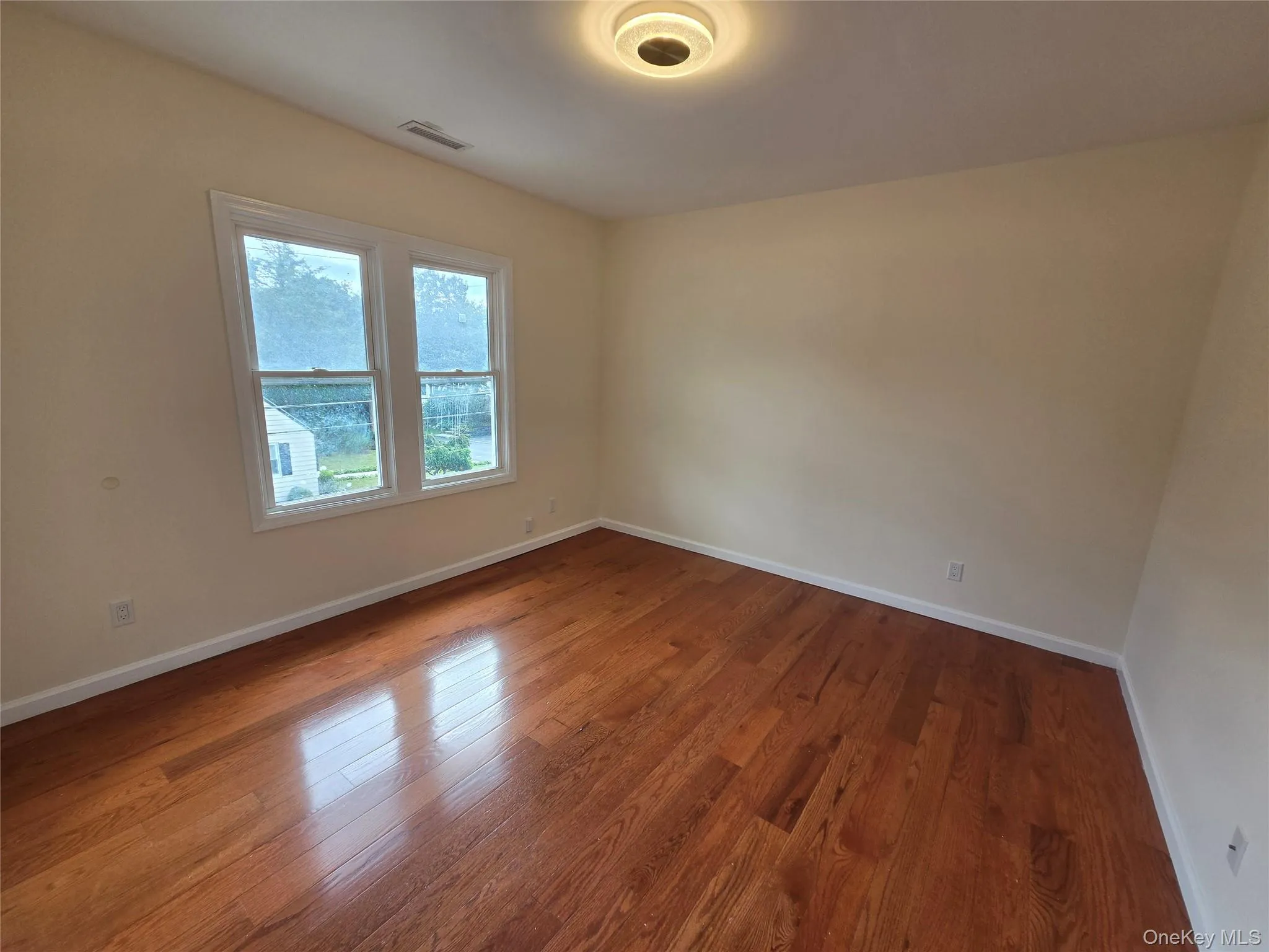 Hardwood flooring, painted walls, two double-hung windows, and a ceiling-mounted light fixture Hardwood flooring, painted walls, two double-hung windows, and a ceiling-mounted light fixture