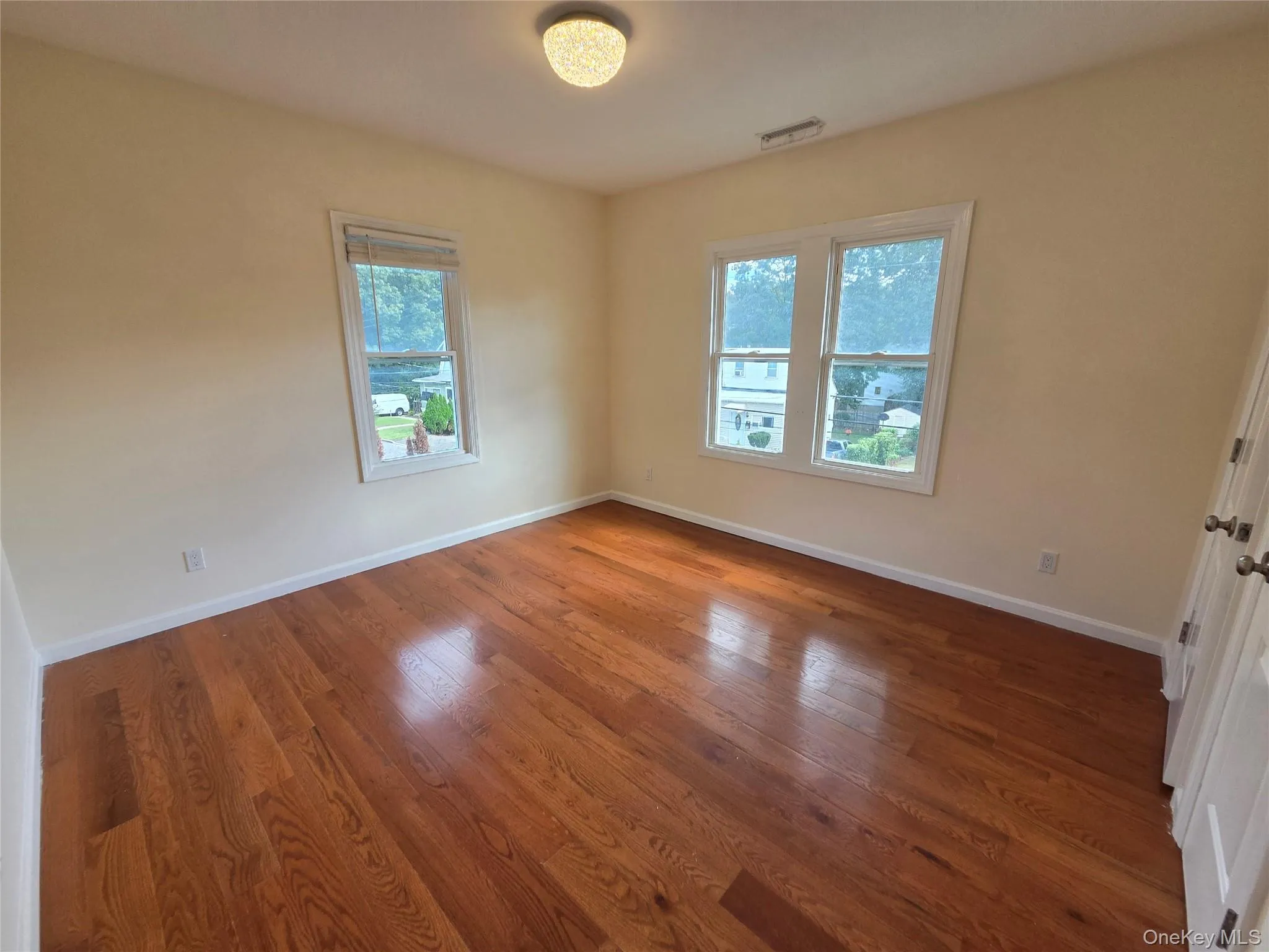 Polished wood flooring, two paneled doors, and two windows Polished wood flooring, two paneled doors, and two windows