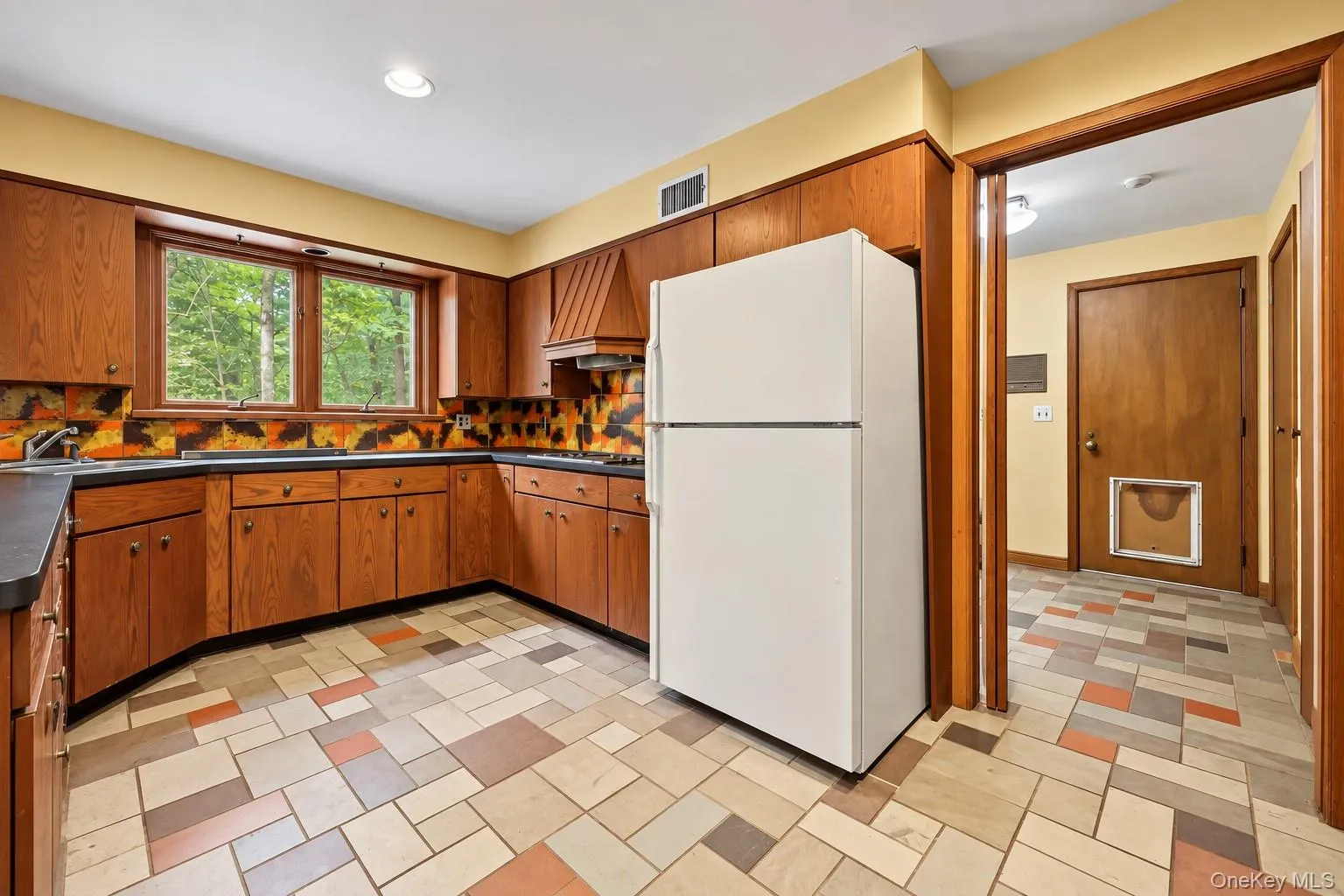 Wood cabinets, stone floor, door on right leads to laundry room, powder room, pantry and backyard. Wood cabinets, stone floor, door on right leads to laundry room, powder room, pantry and backyard.