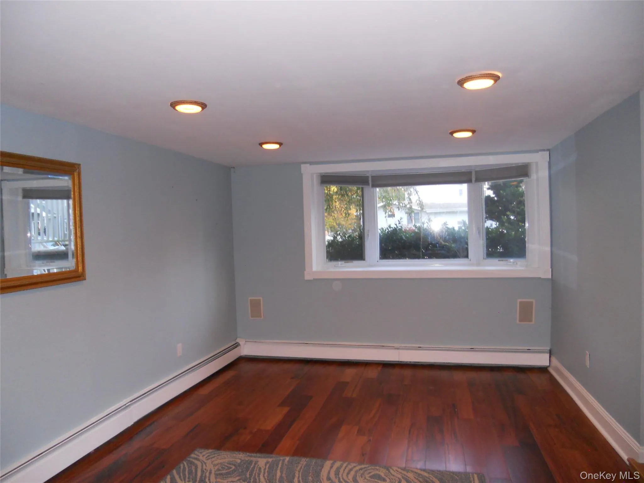 Hardwood flooring, recessed ceiling lighting, bay window, and white trim accents Hardwood flooring, recessed ceiling lighting, bay window, and white trim accents