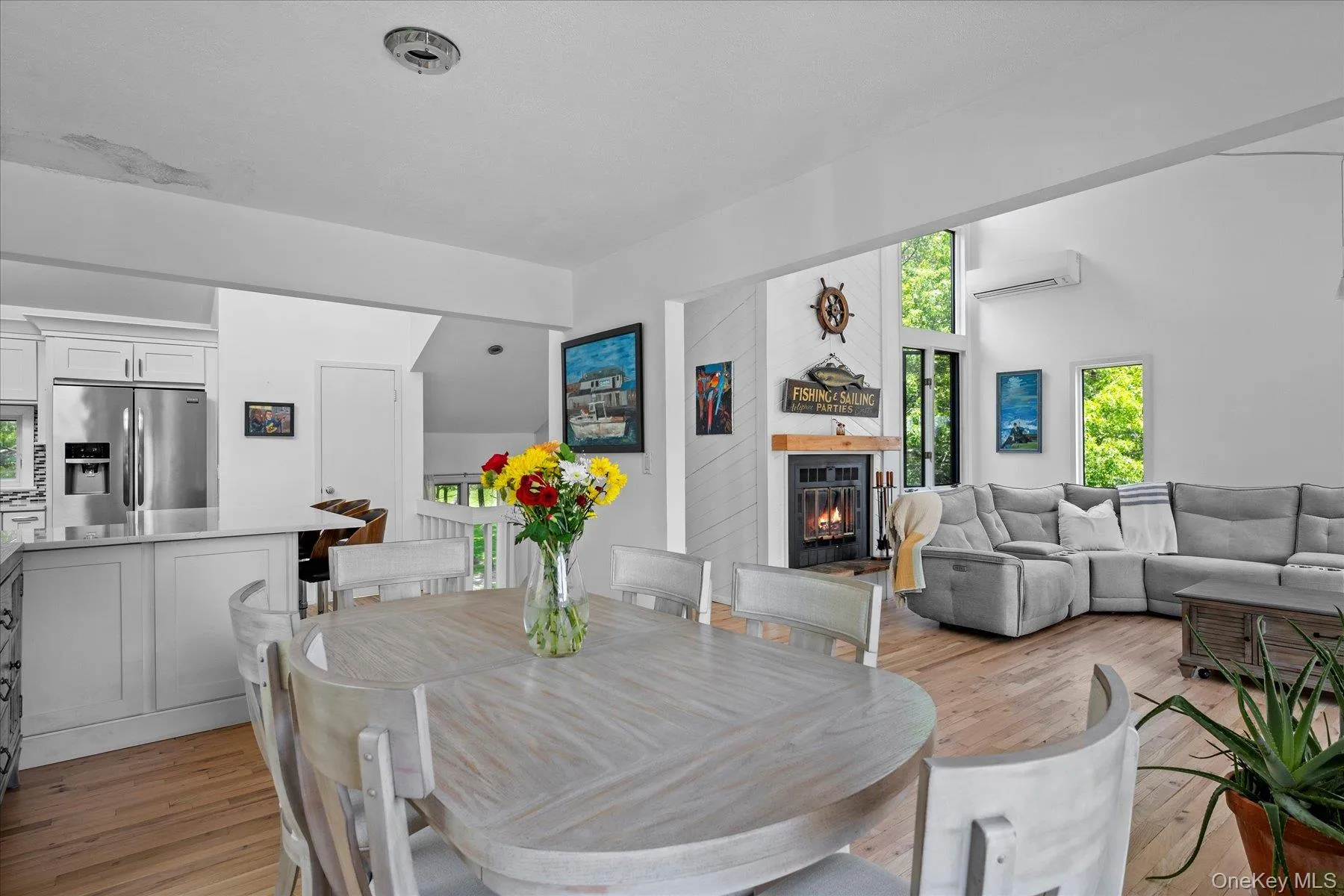 Dining space with light wood-type flooring, a glass covered fireplace, and a wall mounted AC Dining space with light wood-type flooring, a glass covered fireplace, and a wall mounted AC