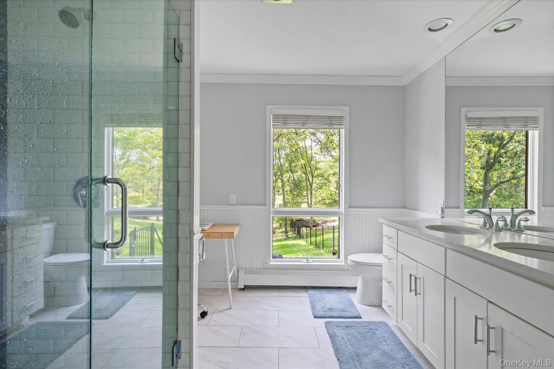 Bathroom with wainscoting, double vanity, ornamental molding, healthy amount of natural light, and a stall shower Bathroom with wainscoting, double vanity, ornamental molding, healthy amount of natural light, and a stall shower