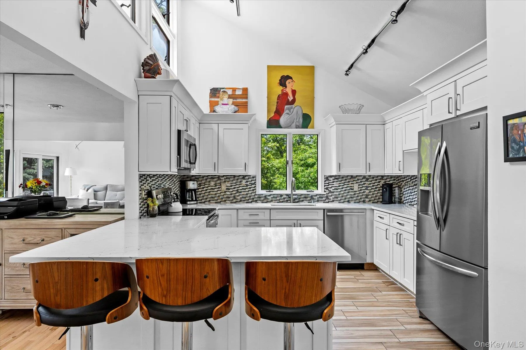 Kitchen with a peninsula, rail lighting, appliances with stainless steel finishes, a breakfast bar area, and tasteful backsplash Kitchen with a peninsula, rail lighting, appliances with stainless steel finishes, a breakfast bar area, and tasteful backsplash