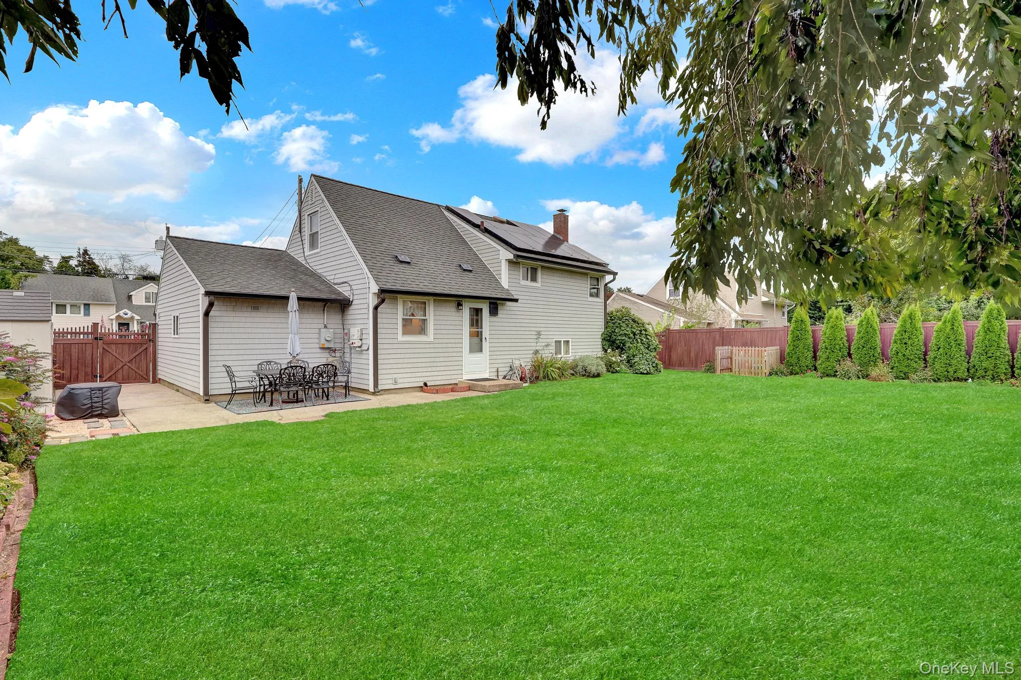 Expansive green lawn, paved patio area, wood fencing, and mature planted trees Expansive green lawn, paved patio area, wood fencing, and mature planted trees