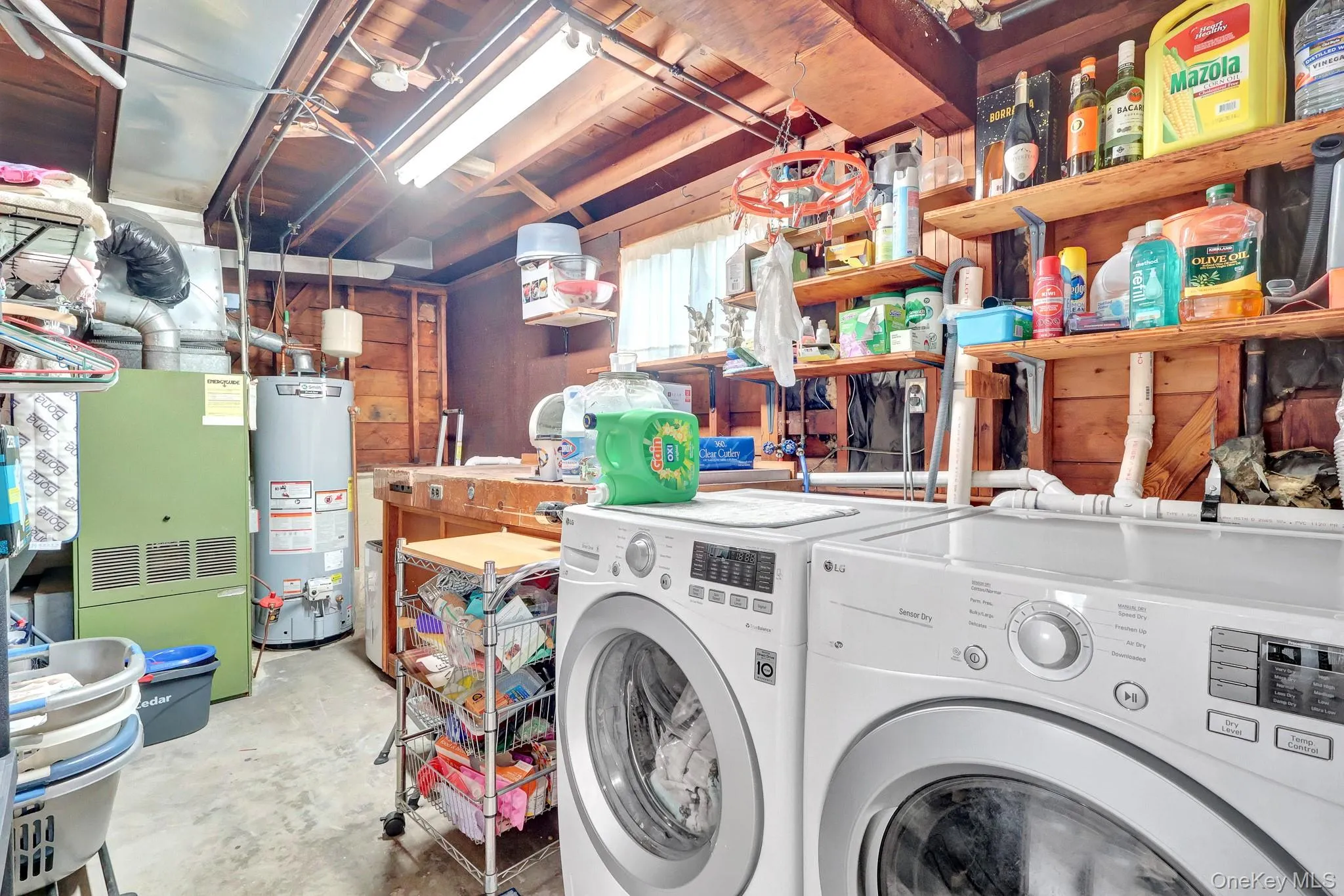 Laundry area with concrete flooring, exposed wood beam ceiling, built-in wooden shelving, and a workbench Laundry area with concrete flooring, exposed wood beam ceiling, built-in wooden shelving, and a workbench