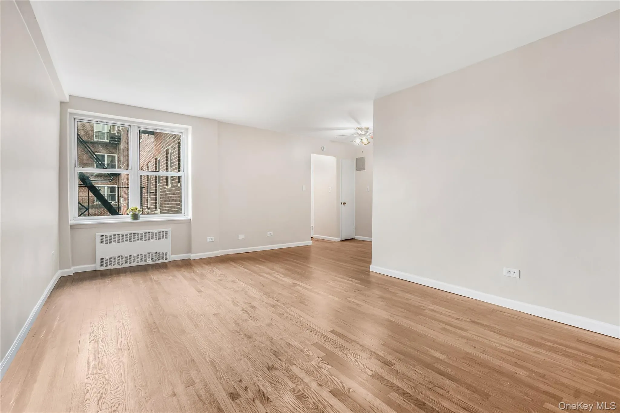 Empty room featuring radiator heating unit and light wood finished floors Empty room featuring radiator heating unit and light wood finished floors