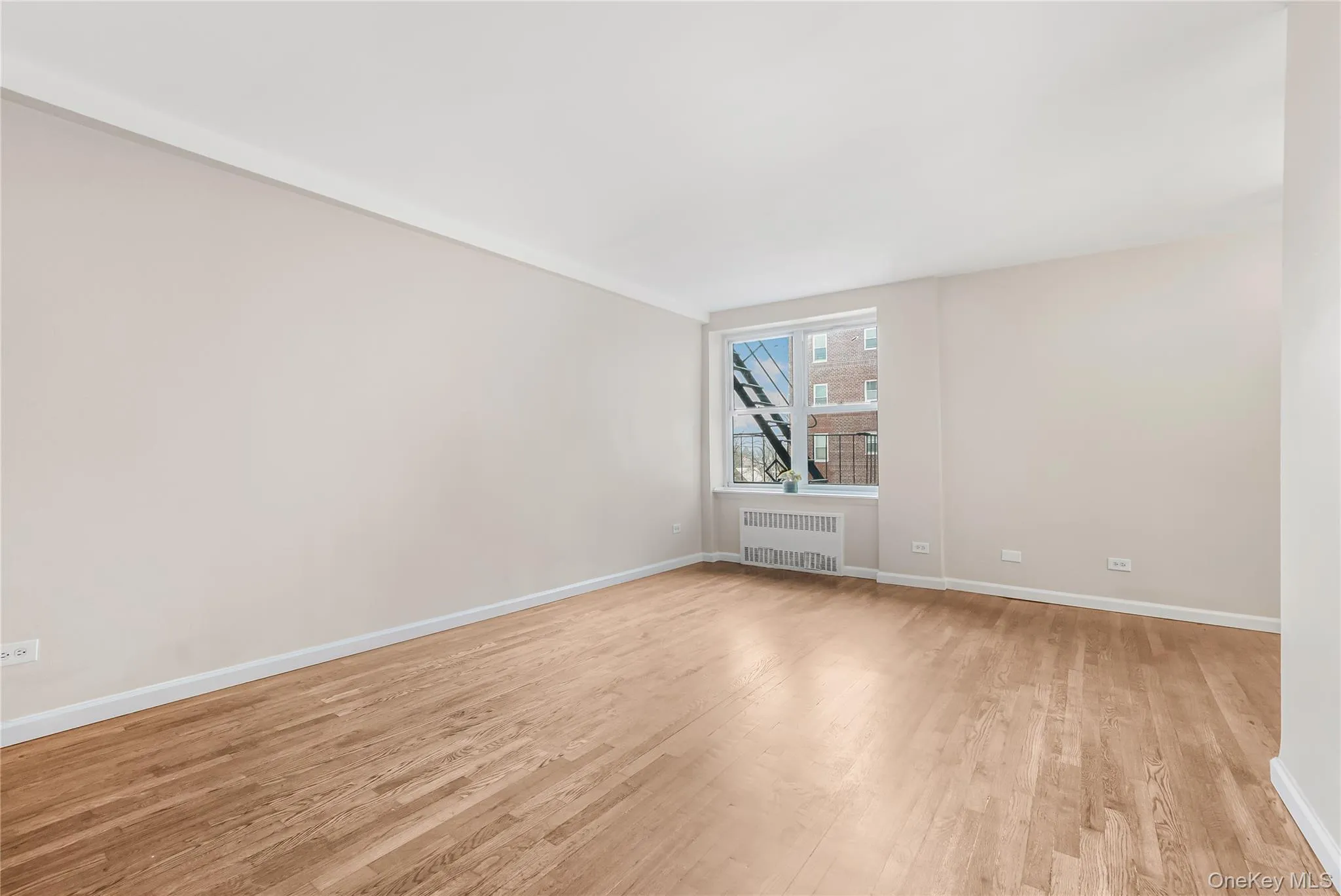 Unfurnished room with light wood-style flooring and radiator Unfurnished room with light wood-style flooring and radiator