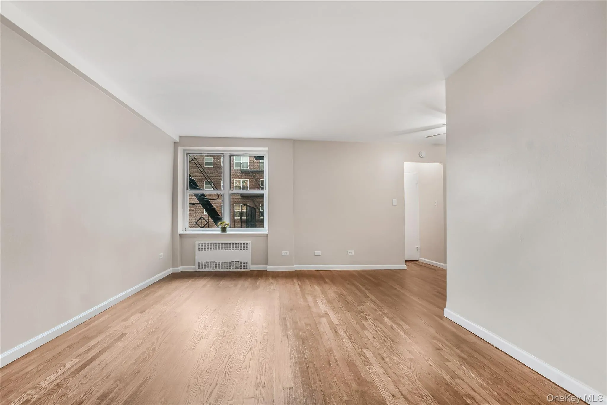 Unfurnished room featuring radiator and light wood-style floors Unfurnished room featuring radiator and light wood-style floors