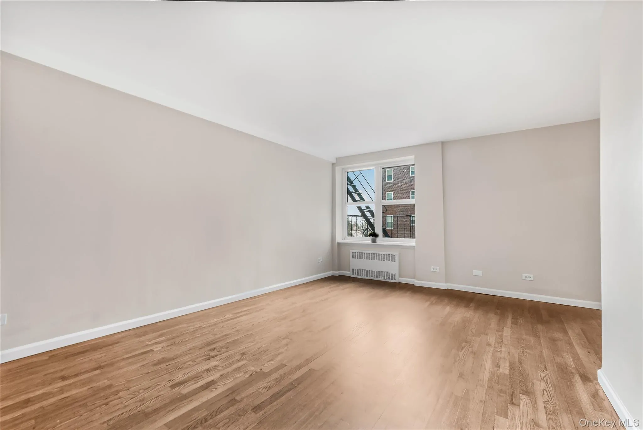 Spare room with light wood finished floors and radiator Spare room with light wood finished floors and radiator