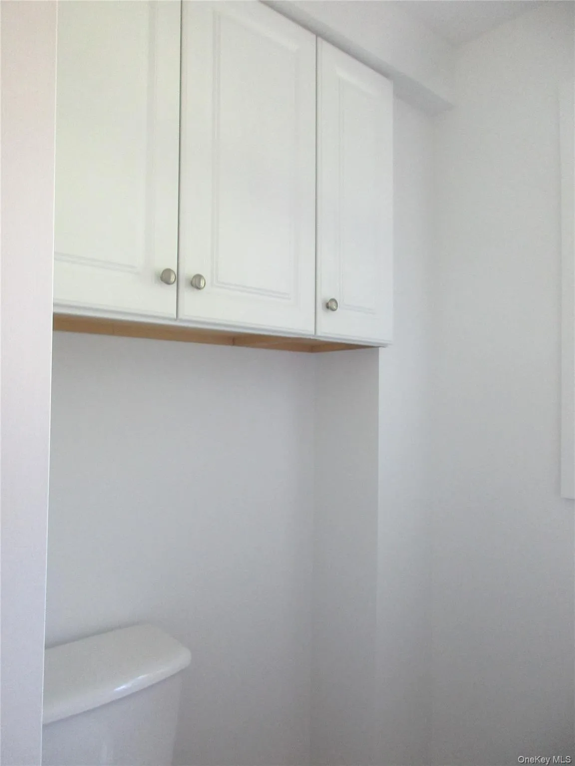 Cabinets about toilet across from sink. Cabinets about toilet across from sink.