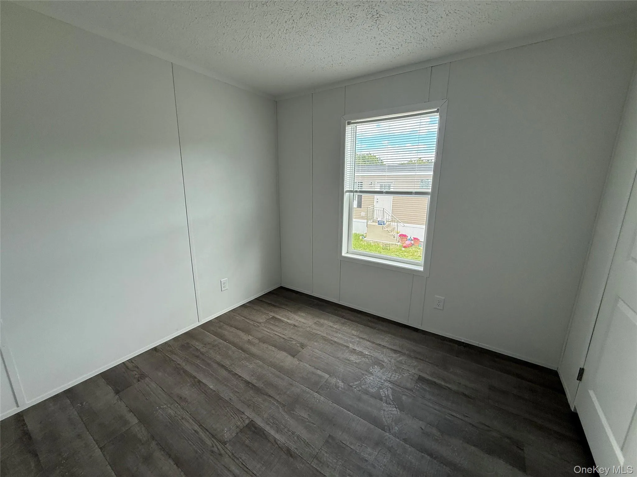 Spare room with a textured ceiling and dark wood finished floors Spare room with a textured ceiling and dark wood finished floors