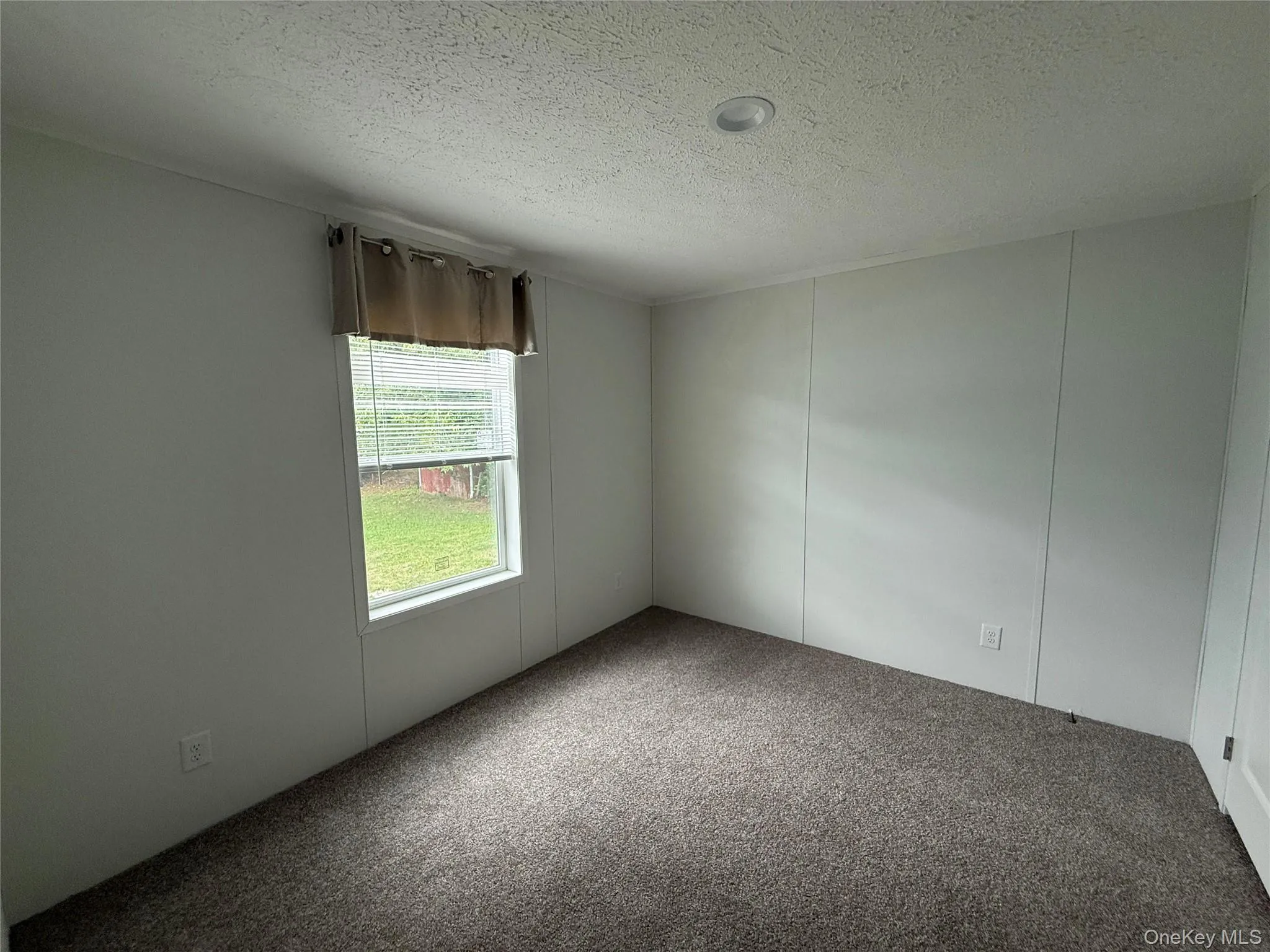 Unfurnished room with a textured ceiling, carpet, and a decorative wall Unfurnished room with a textured ceiling, carpet, and a decorative wall