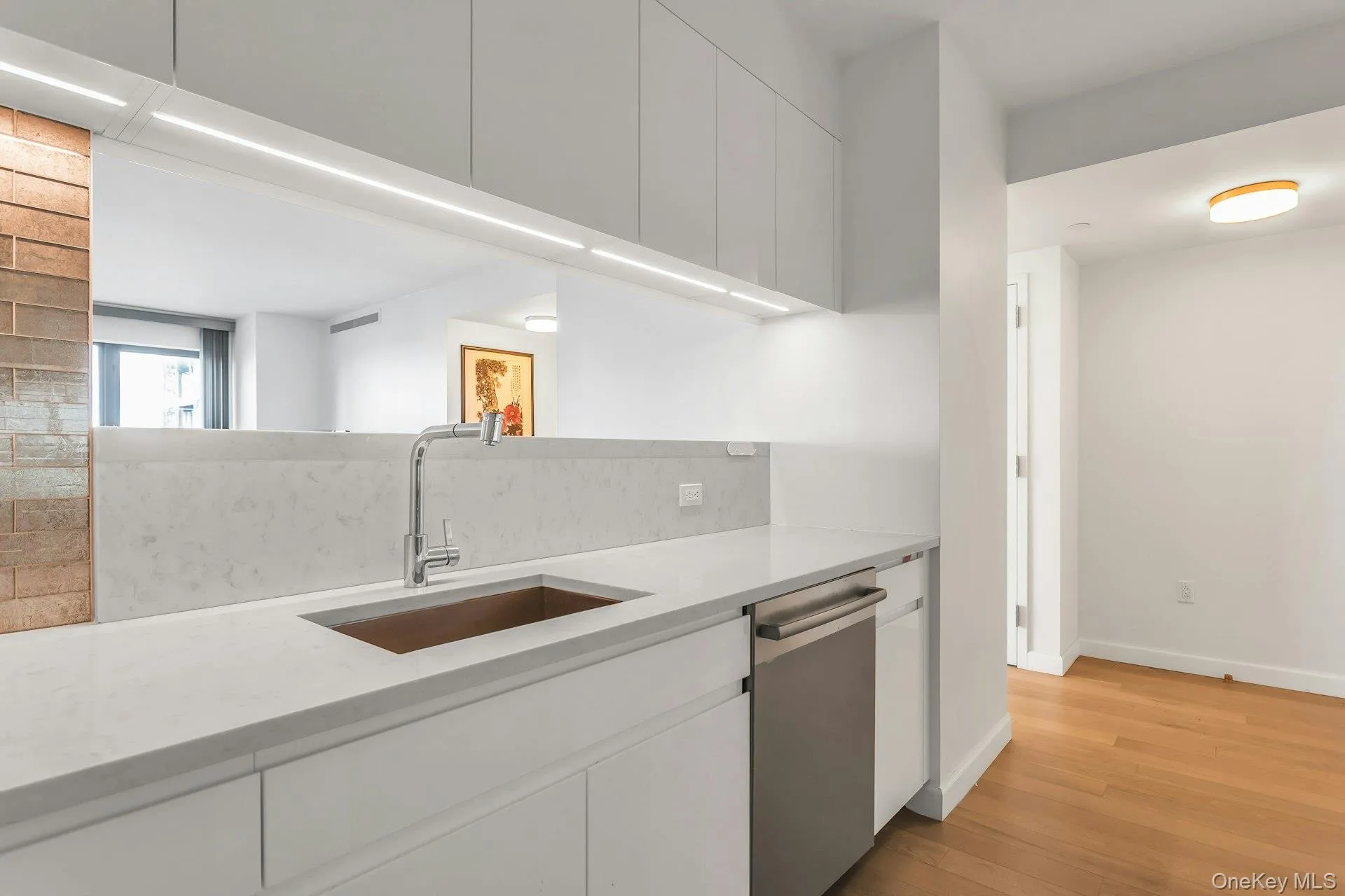 Kitchen featuring stainless steel dishwasher, light stone countertops, white cabinetry, light wood-style flooring, and modern cabinets Kitchen featuring stainless steel dishwasher, light stone countertops, white cabinetry, light wood-style flooring, and modern cabinets