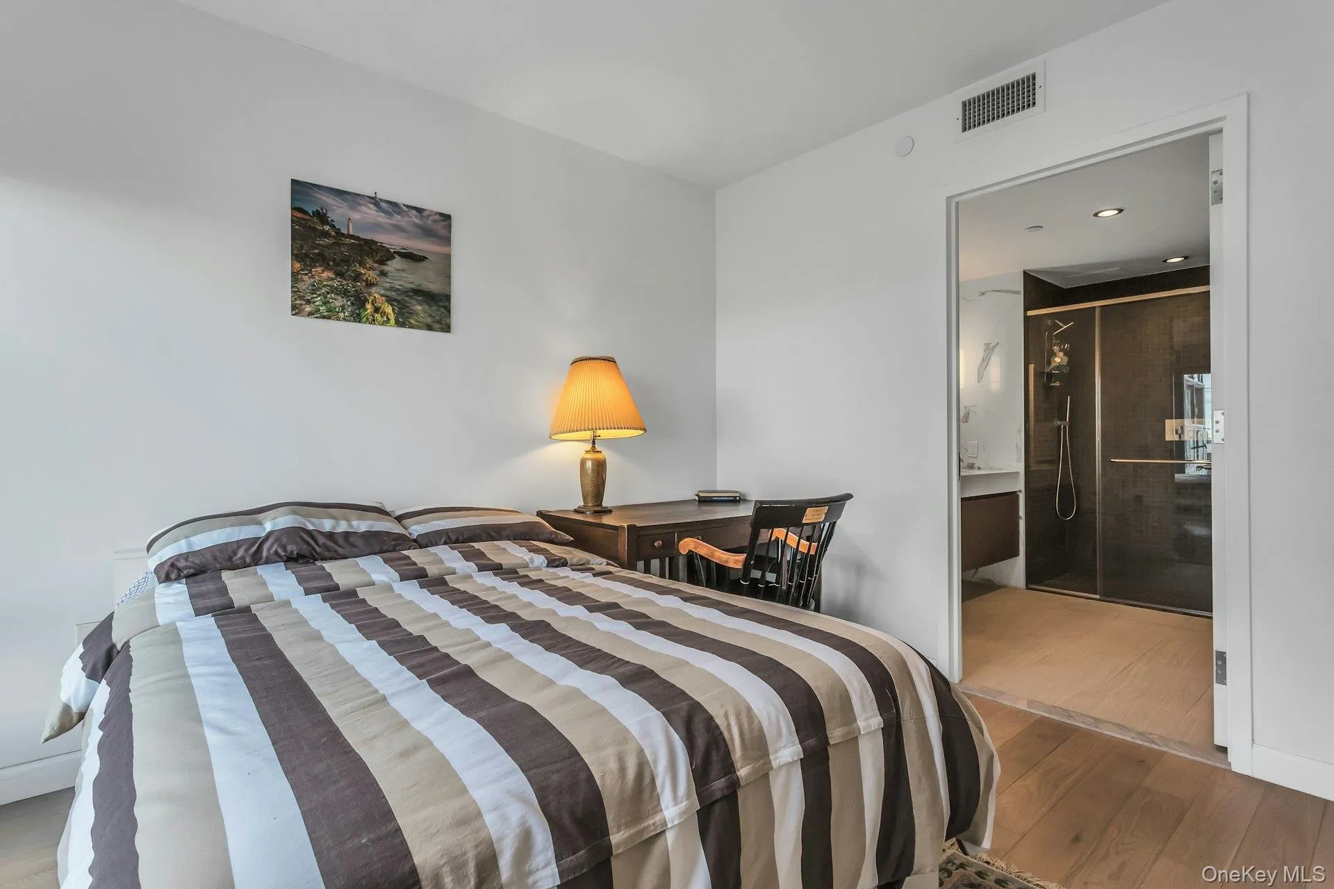 Bedroom featuring wood finished floors and ensuite bath Bedroom featuring wood finished floors and ensuite bath