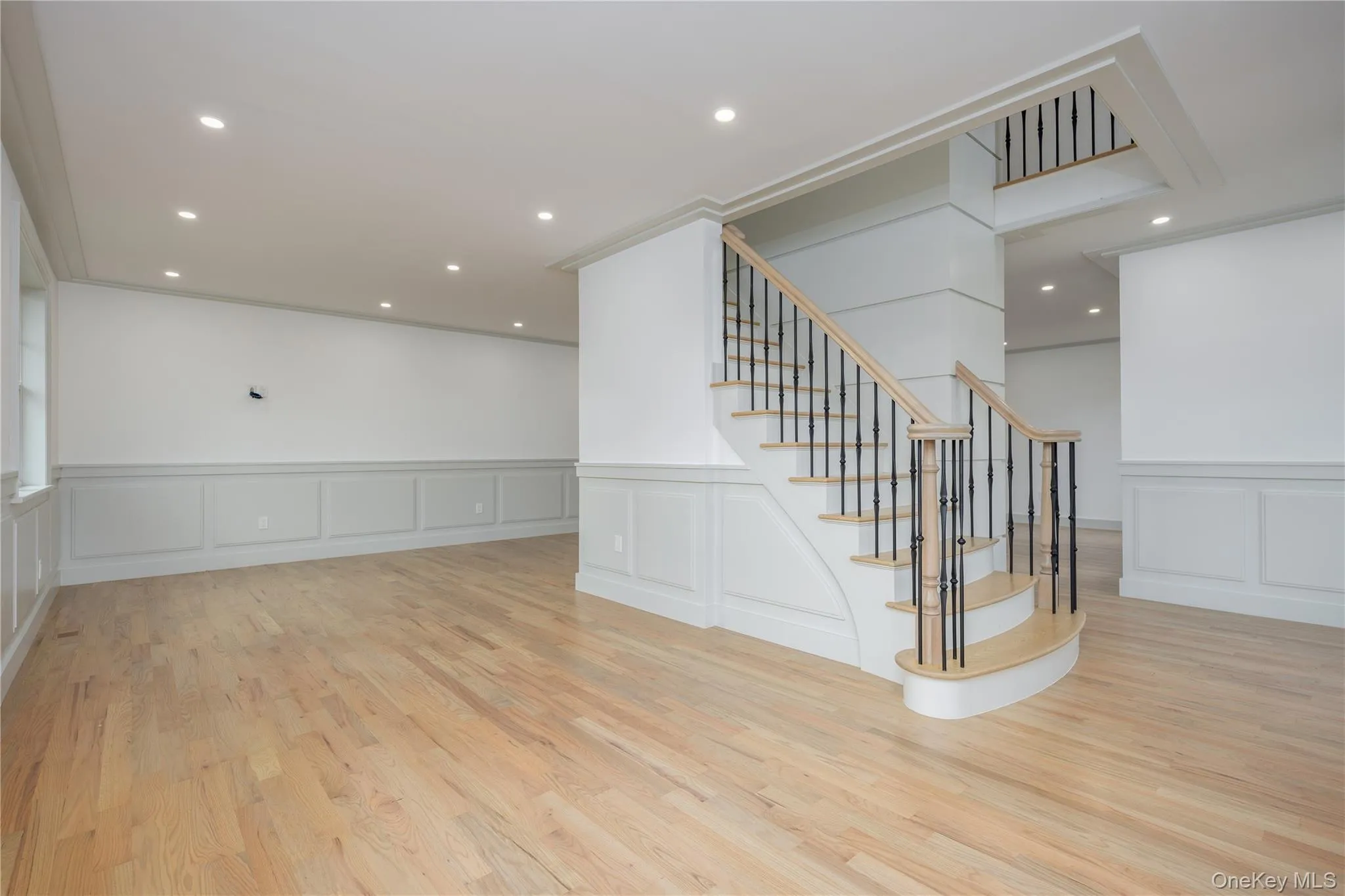 Stairway with a decorative wall, wood finished floors, a wainscoted wall, and recessed lighting Stairway with a decorative wall, wood finished floors, a wainscoted wall, and recessed lighting