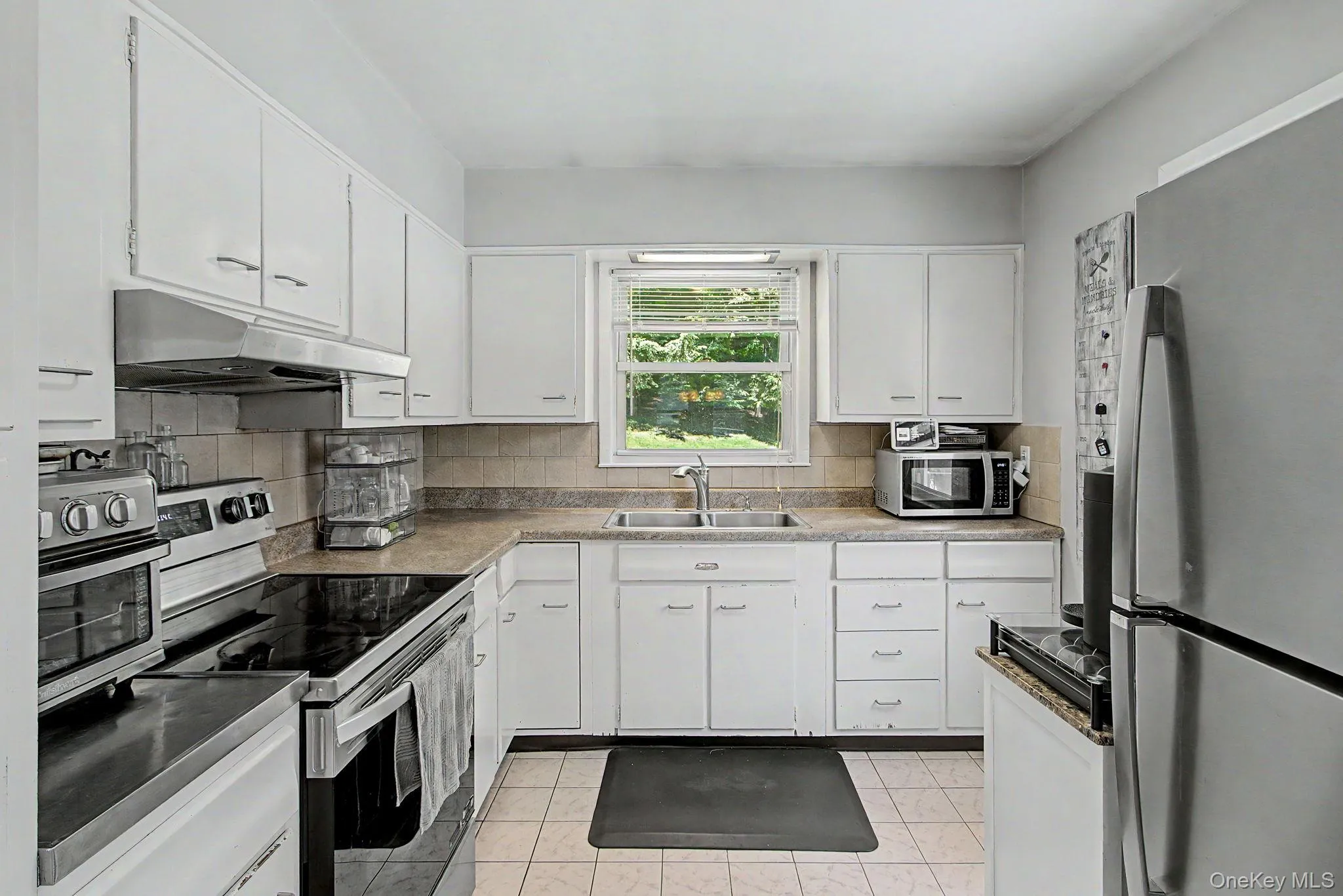 Kitchen with stainless steel appliances, white cabinetry, and tile flooring. Kitchen with stainless steel appliances, white cabinetry, and tile flooring.