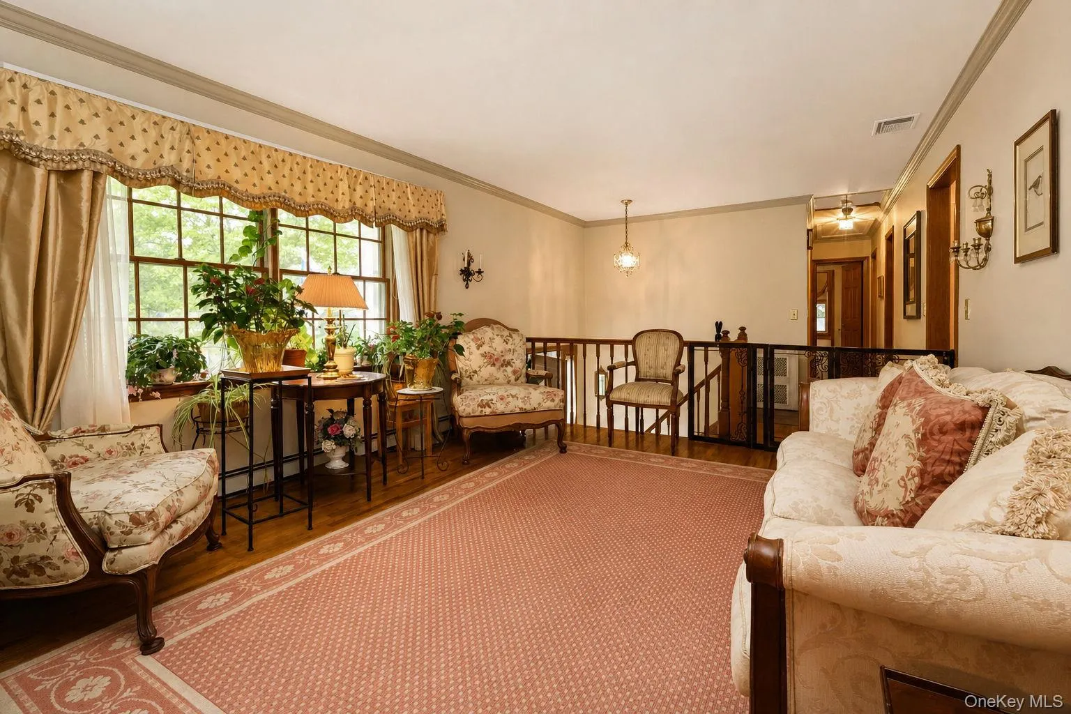 Hardwood flooring with an area rug, a built-in wall sconce, and a window with a valance wood railings Hardwood flooring with an area rug, a built-in wall sconce, and a window with a valance wood railings