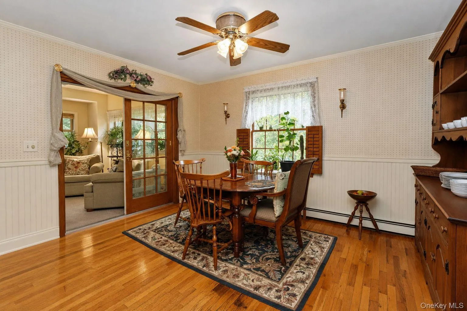 Breakfast nook hardwood flooring, paneled wainscoting, glass-paneled sliding doors, window with interior shutters, and a ceiling fan with integrated lighting Breakfast nook hardwood flooring, paneled wainscoting, glass-paneled sliding doors, window with interior shutters, and a ceiling fan with integrated lighting