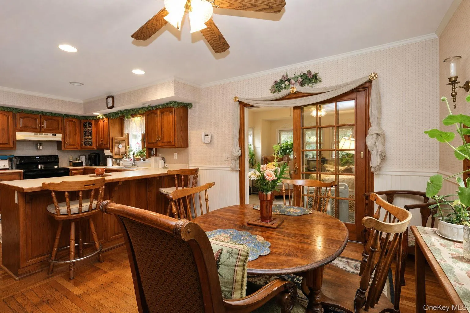 Wood-finish flooring, wood cabinetry, built-in ceiling lighting, and a ceiling fan Peninsula with storage and entrance to the bonus room Wood-finish flooring, wood cabinetry, built-in ceiling lighting, and a ceiling fan Peninsula with storage and entrance to the bonus room