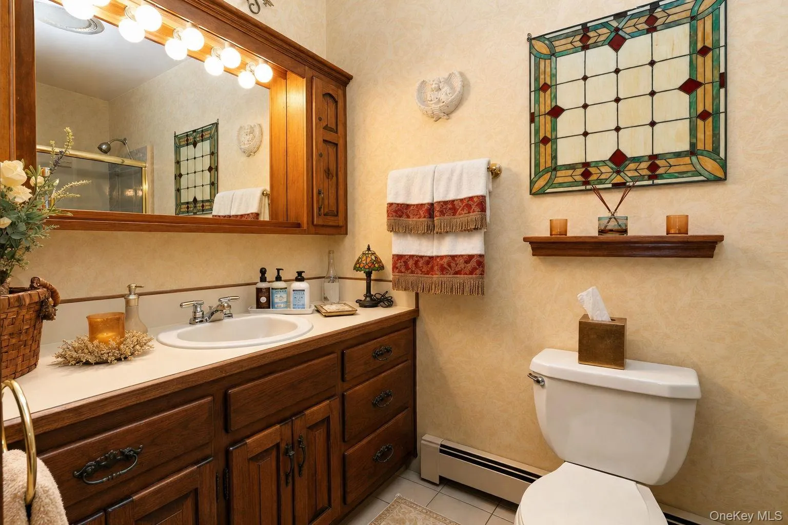 Warm-toned vanity with an integrated sink, ample storage cabinetry and tub/shower Warm-toned vanity with an integrated sink, ample storage cabinetry and tub/shower