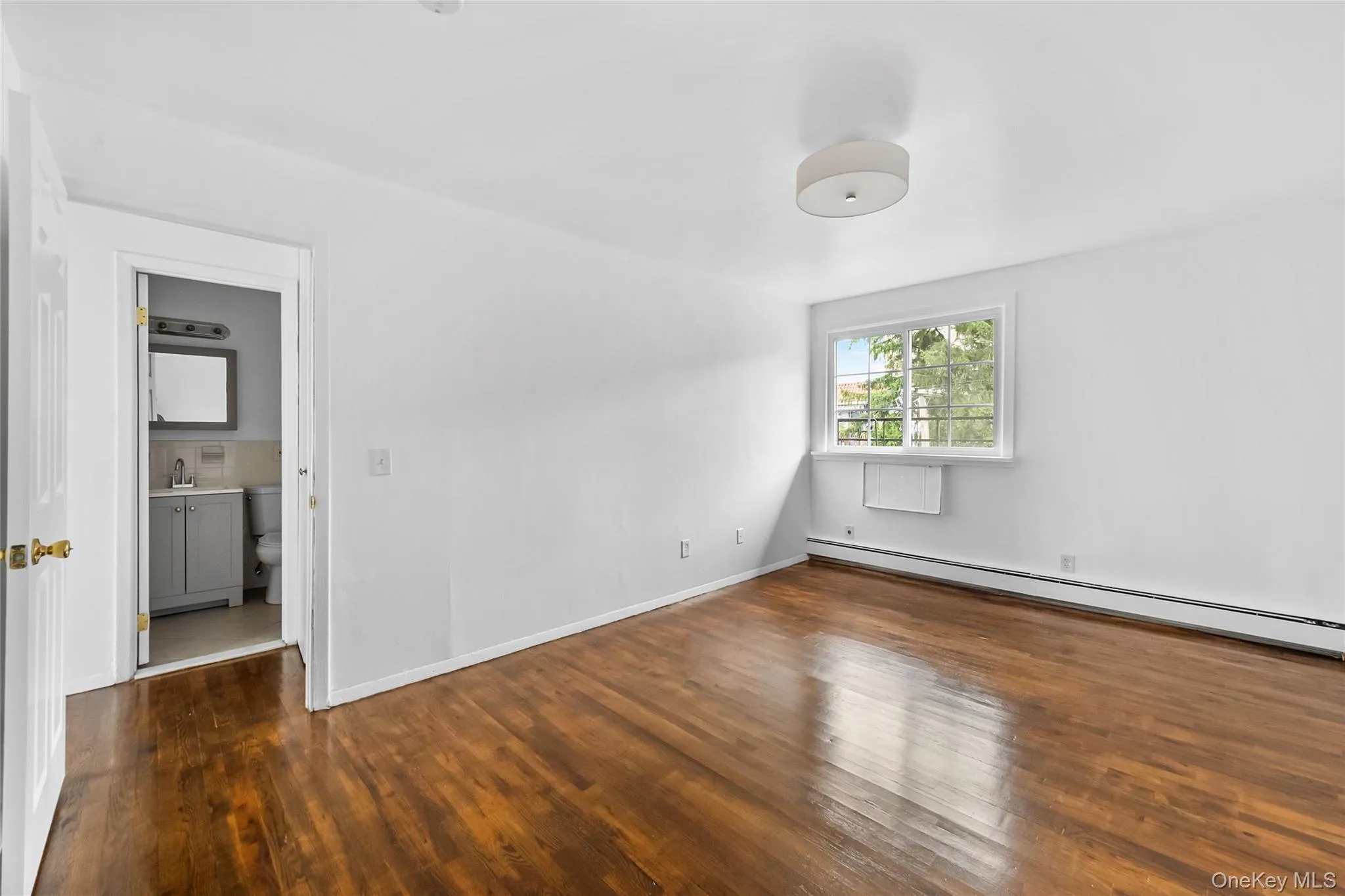Empty room featuring dark wood-style flooring and a baseboard heating unit Empty room featuring dark wood-style flooring and a baseboard heating unit