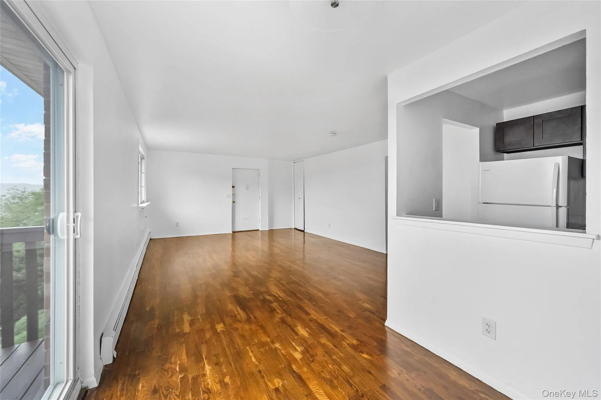 Unfurnished room featuring dark wood finished floors and a baseboard radiator Unfurnished room featuring dark wood finished floors and a baseboard radiator