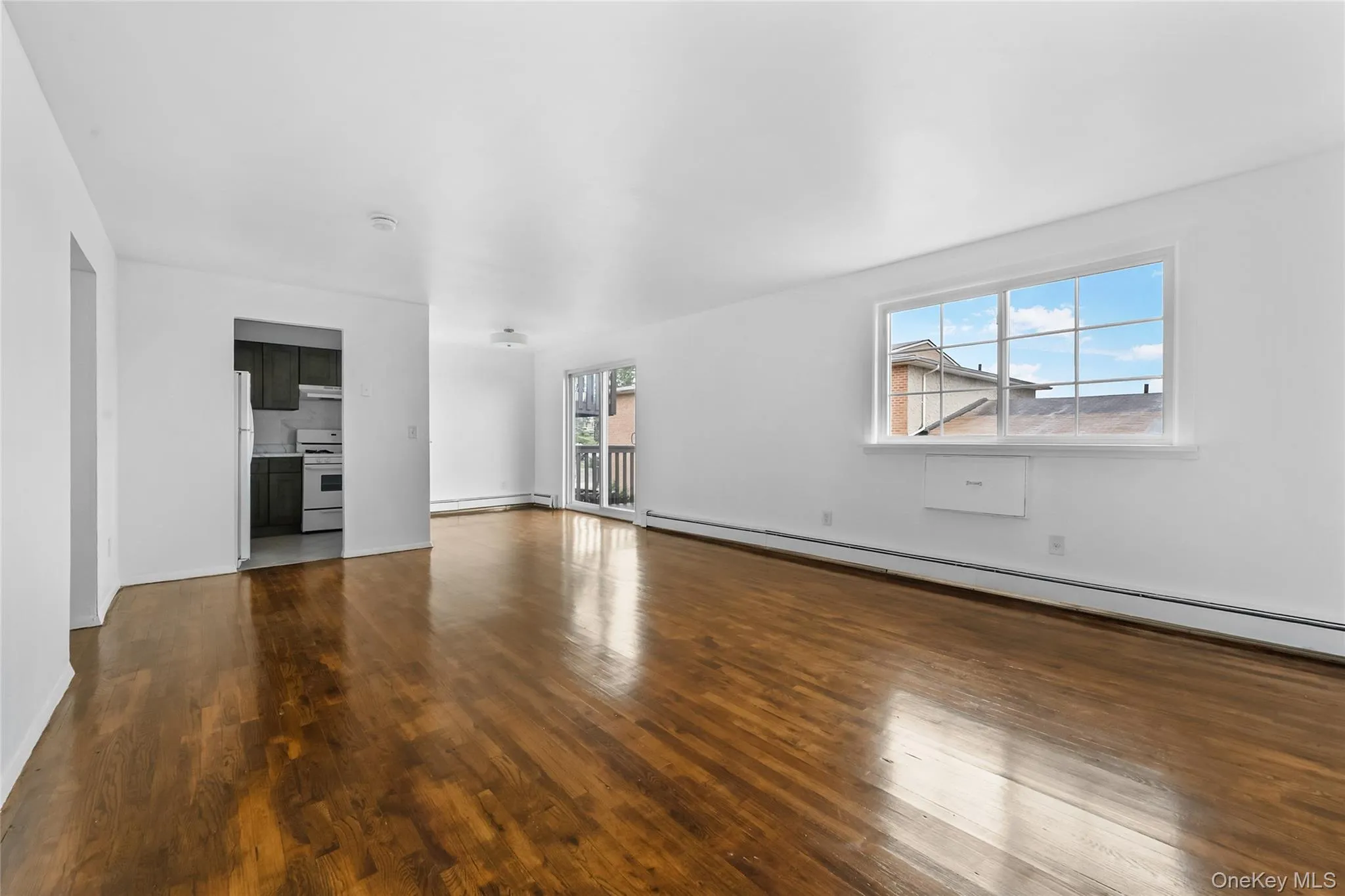 Unfurnished living room featuring a baseboard radiator, dark wood-type flooring, and baseboard heating Unfurnished living room featuring a baseboard radiator, dark wood-type flooring, and baseboard heating