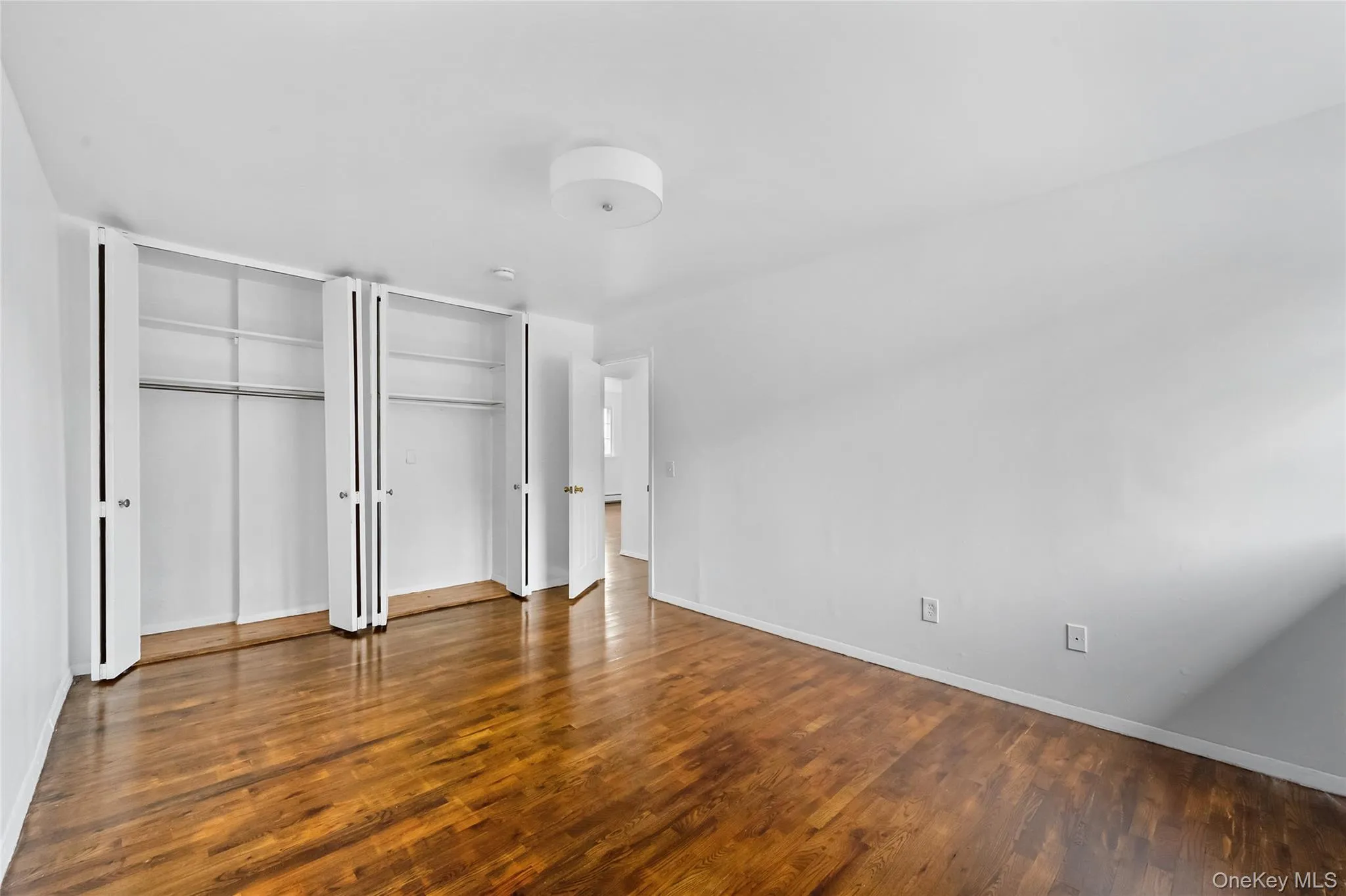 Unfurnished bedroom featuring multiple closets and dark wood finished floors Unfurnished bedroom featuring multiple closets and dark wood finished floors