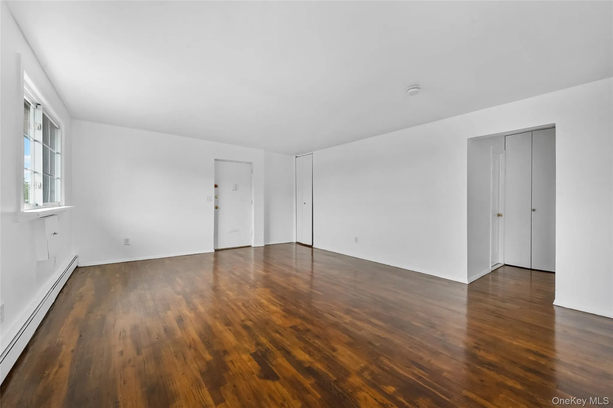 Spare room featuring a baseboard radiator and dark wood-type flooring Spare room featuring a baseboard radiator and dark wood-type flooring