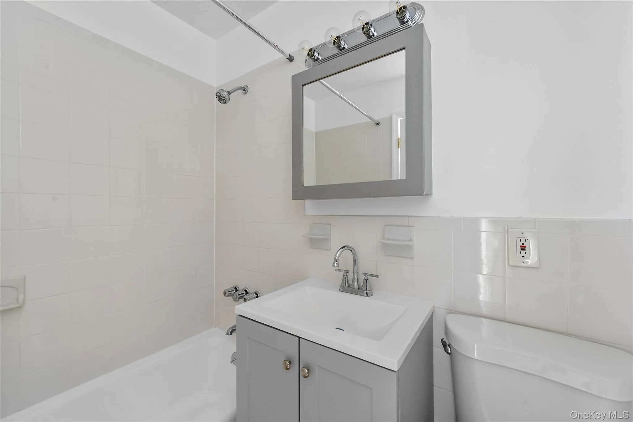 Bathroom featuring tub / shower combination, vanity, and tile walls Bathroom featuring tub / shower combination, vanity, and tile walls