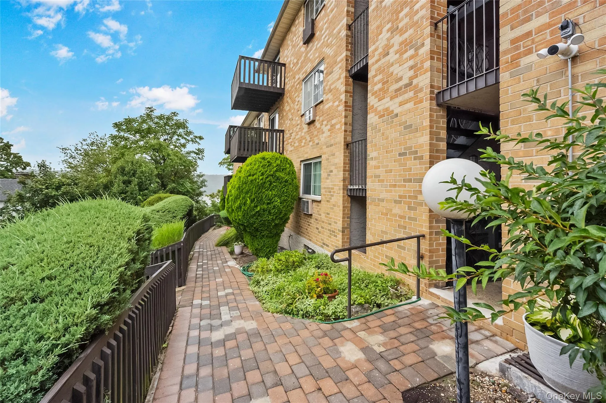 View of side of home featuring brick siding, a balcony, and a security system View of side of home featuring brick siding, a balcony, and a security system