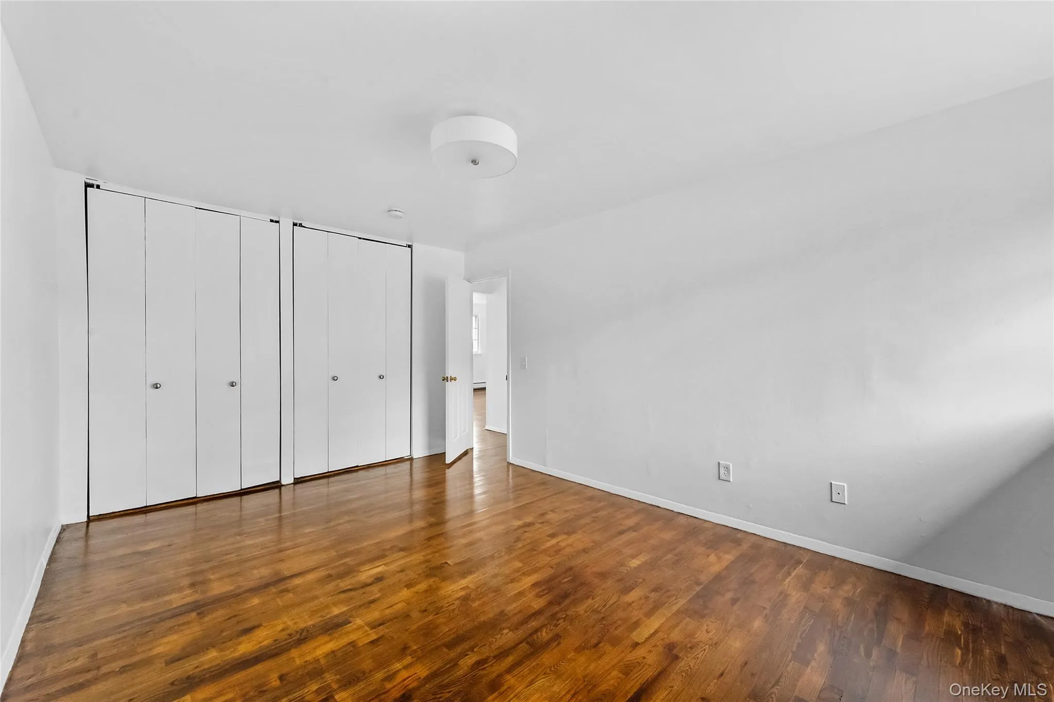 Unfurnished bedroom with two closets and dark wood finished floors Unfurnished bedroom with two closets and dark wood finished floors