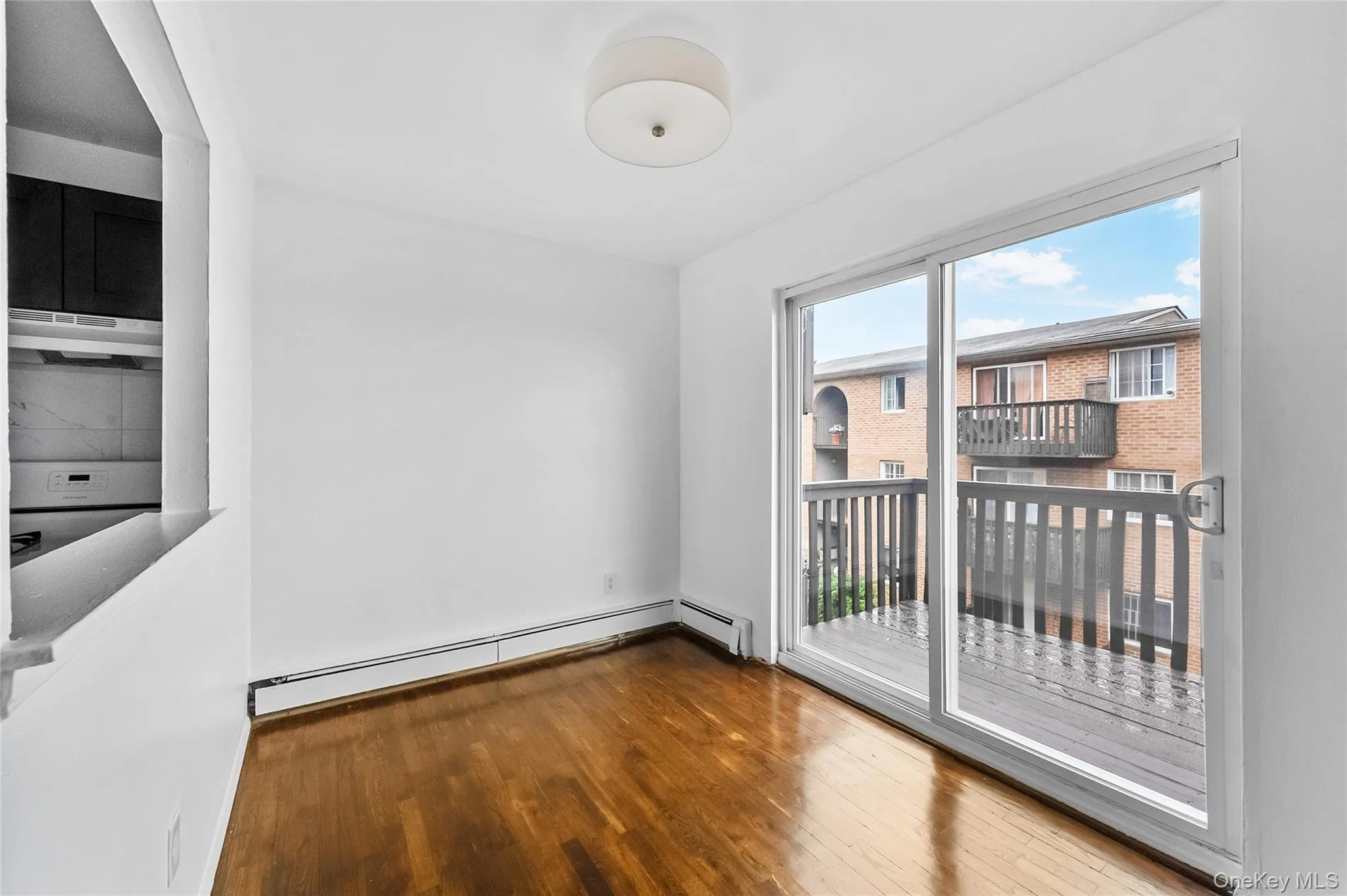 Unfurnished room featuring wood finished floors and baseboard heating Unfurnished room featuring wood finished floors and baseboard heating