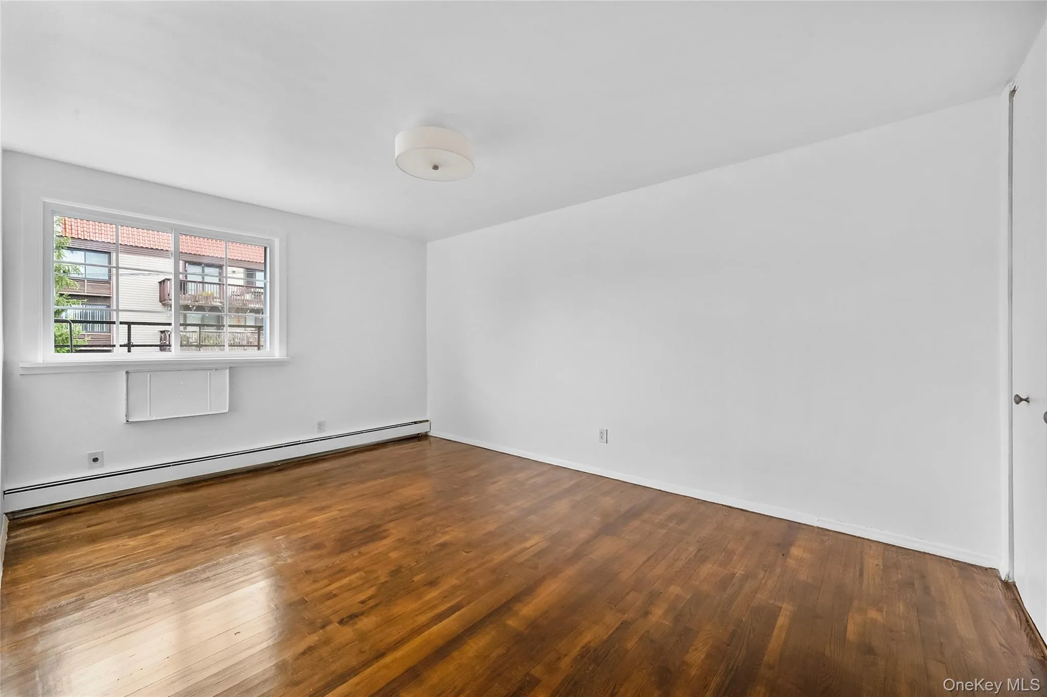 Unfurnished room with a baseboard heating unit and dark wood-style flooring Unfurnished room with a baseboard heating unit and dark wood-style flooring