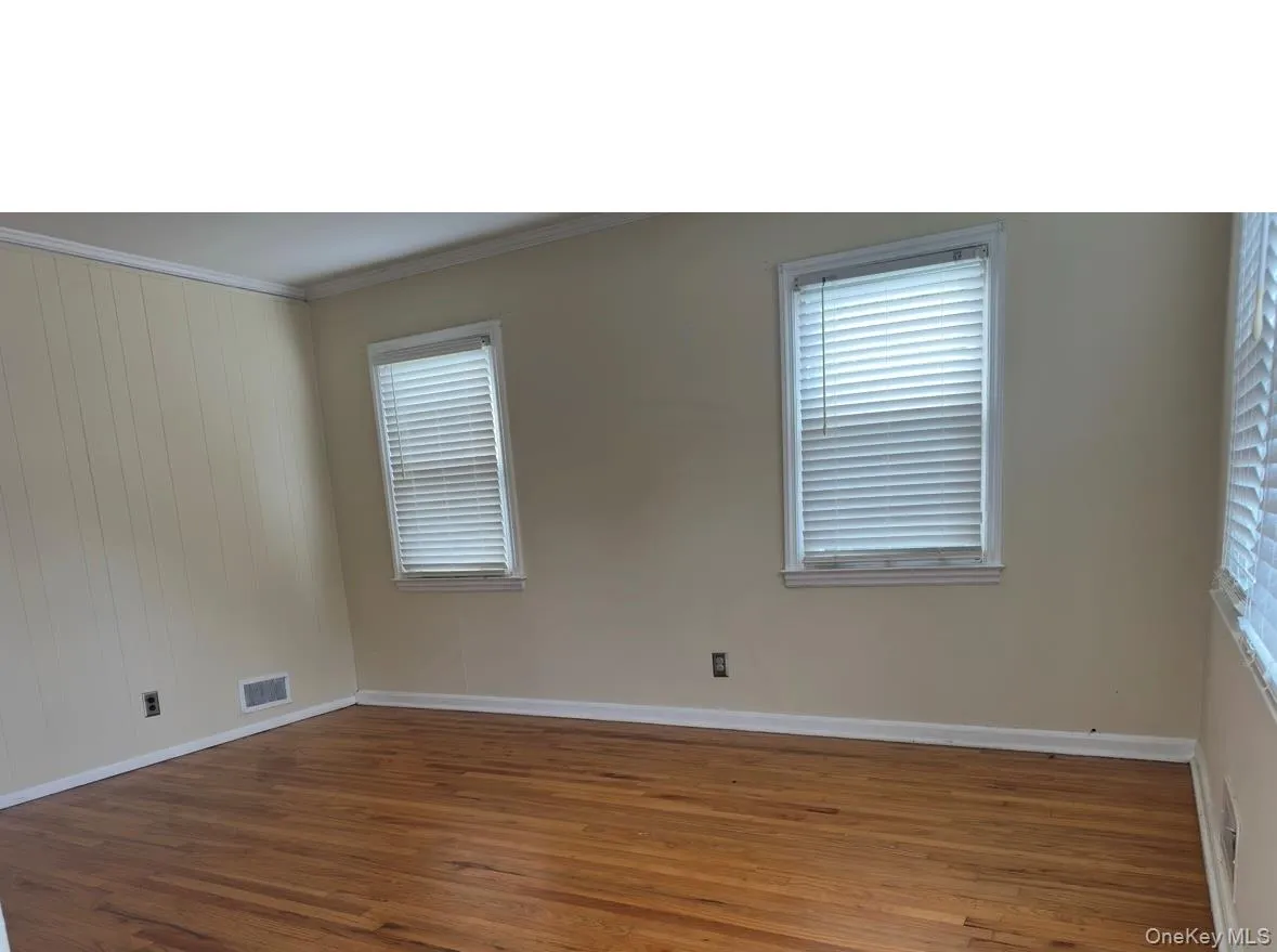Empty room featuring ornamental molding and wood finished floors Empty room featuring ornamental molding and wood finished floors