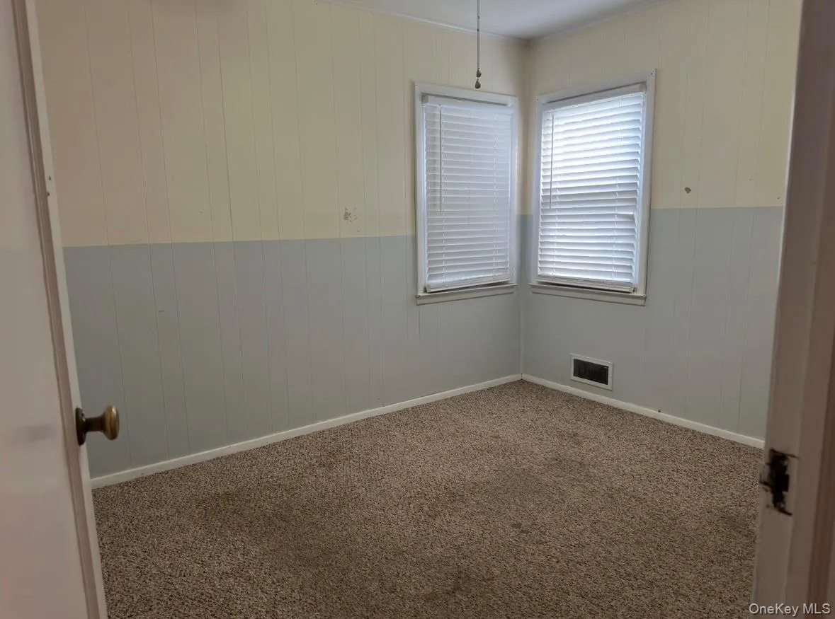 Spare room featuring wood walls and carpet Spare room featuring wood walls and carpet