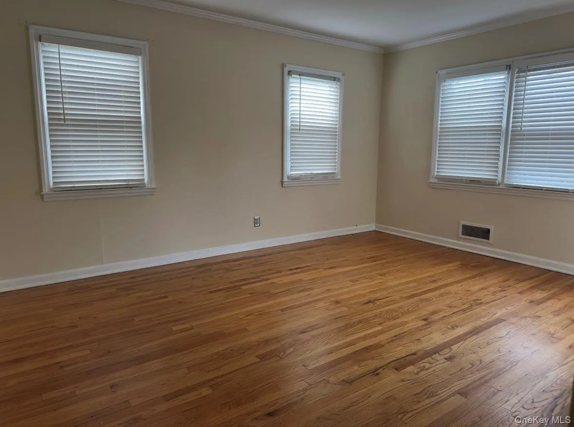 Empty room with ornamental molding and wood finished floors Empty room with ornamental molding and wood finished floors