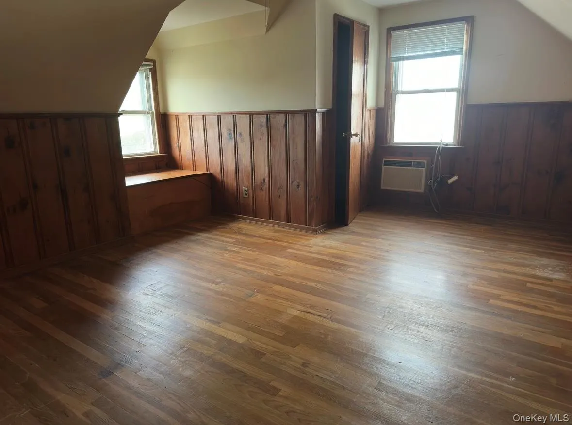 Bedroom with dark wood-style flooring, wainscoting, lofted ceiling, and wood walls Bedroom with dark wood-style flooring, wainscoting, lofted ceiling, and wood walls