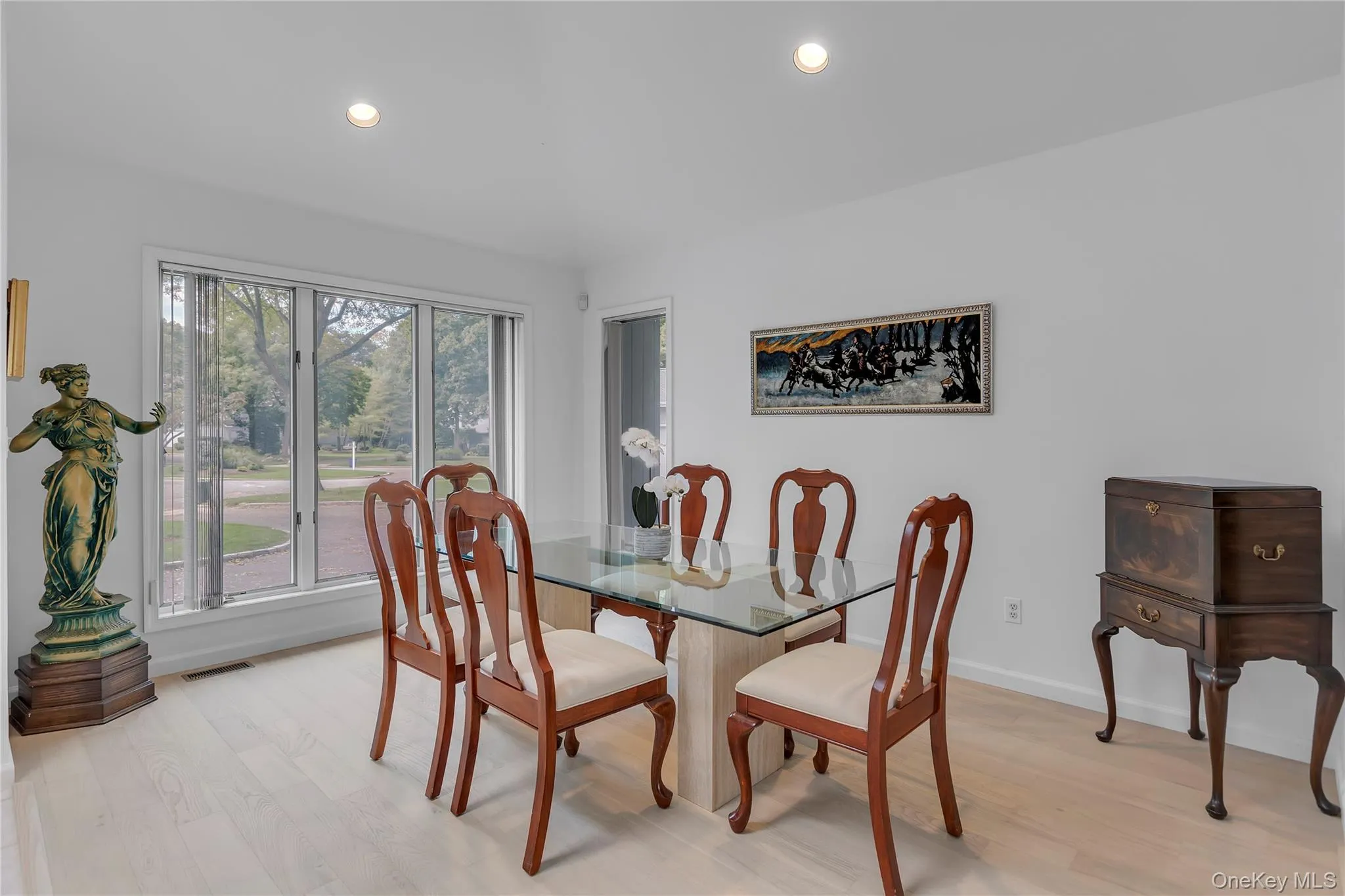 Bright dining area featuring a three-panel window, recessed ceiling lighting, and wood floors. Bright dining area featuring a three-panel window, recessed ceiling lighting, and wood floors.
